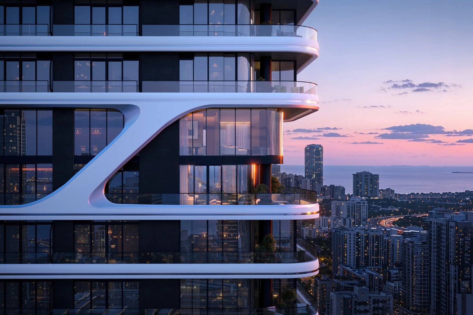 Modern high-rise tower with sweeping balconies overlooking a coastal city at sunset.