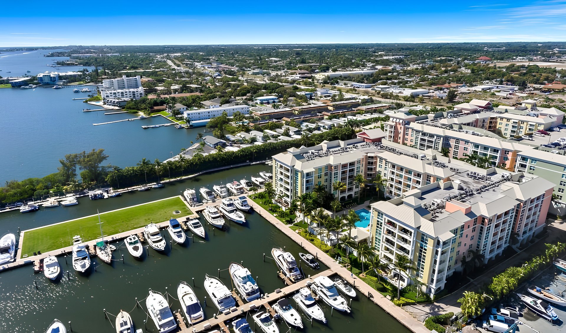 Waterfront apartments beside a marina filled with boats, seen from above.