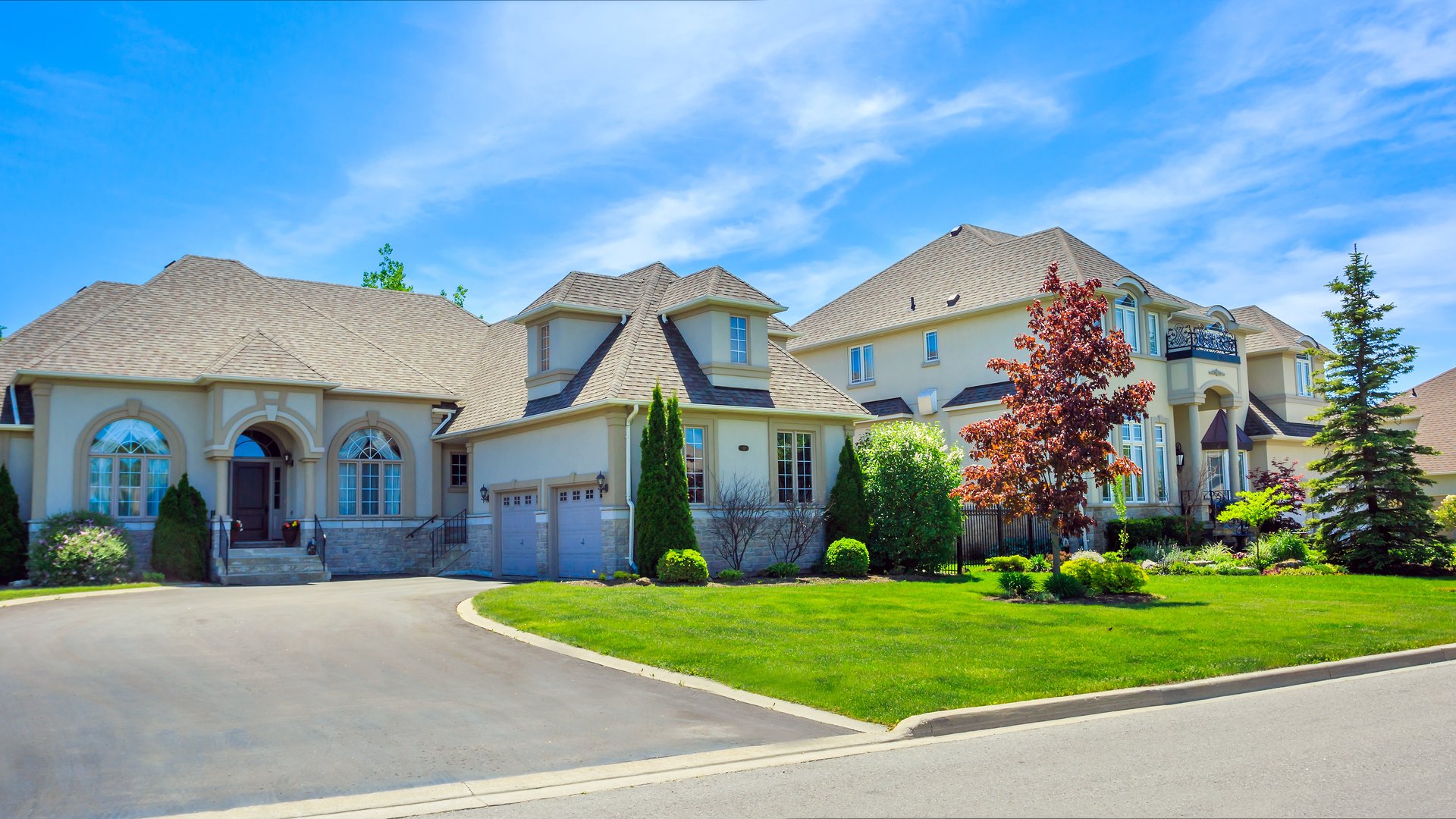 Two grand luxury custom homes with manicured green lawns and stone facades in an affluent Oakville neighbourhood, illustrating prestige real estate in Eastlake and Old Oakville.