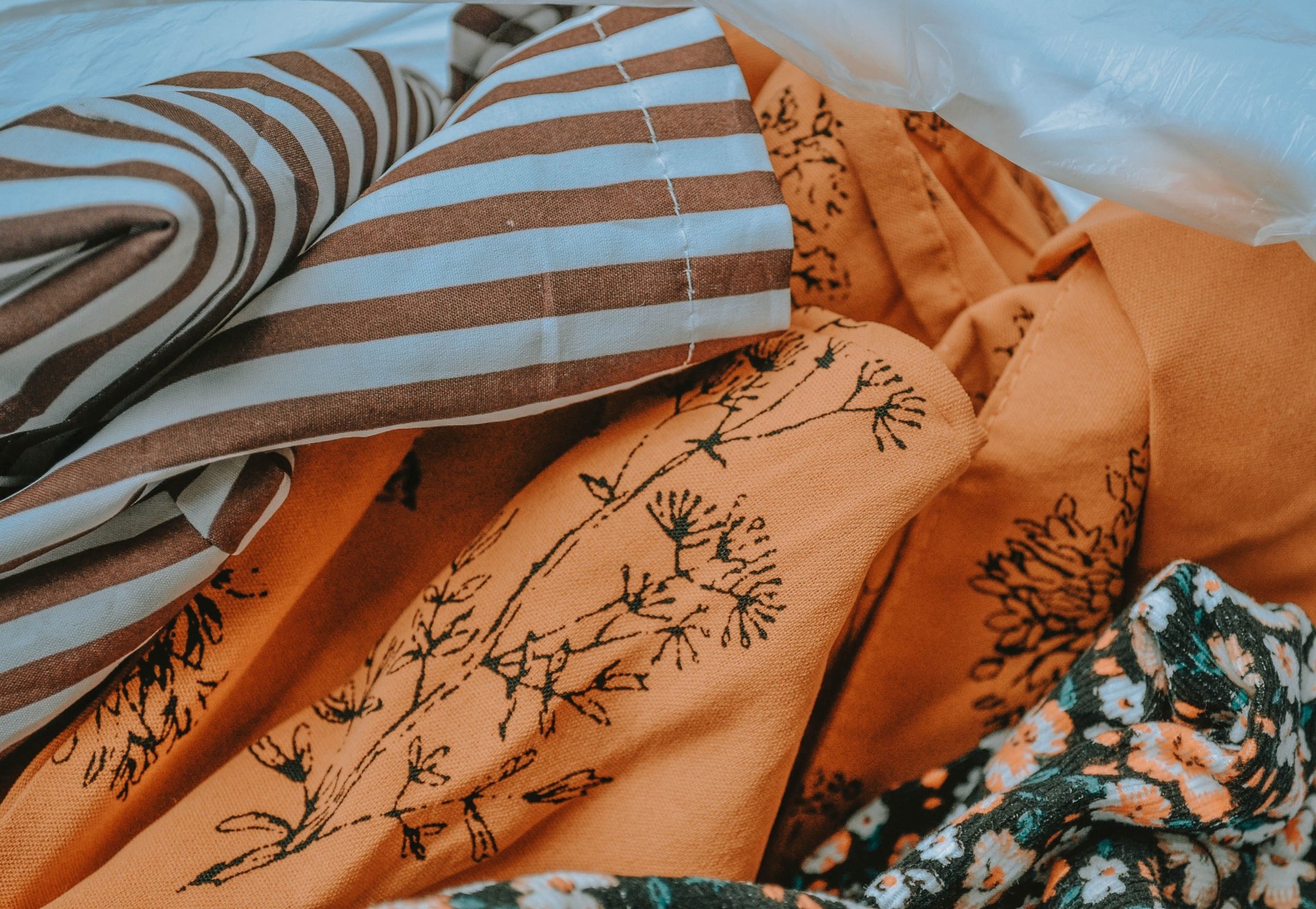 Layered rust-colored fabrics with botanical prints and blue-and-rust striped upholstery.