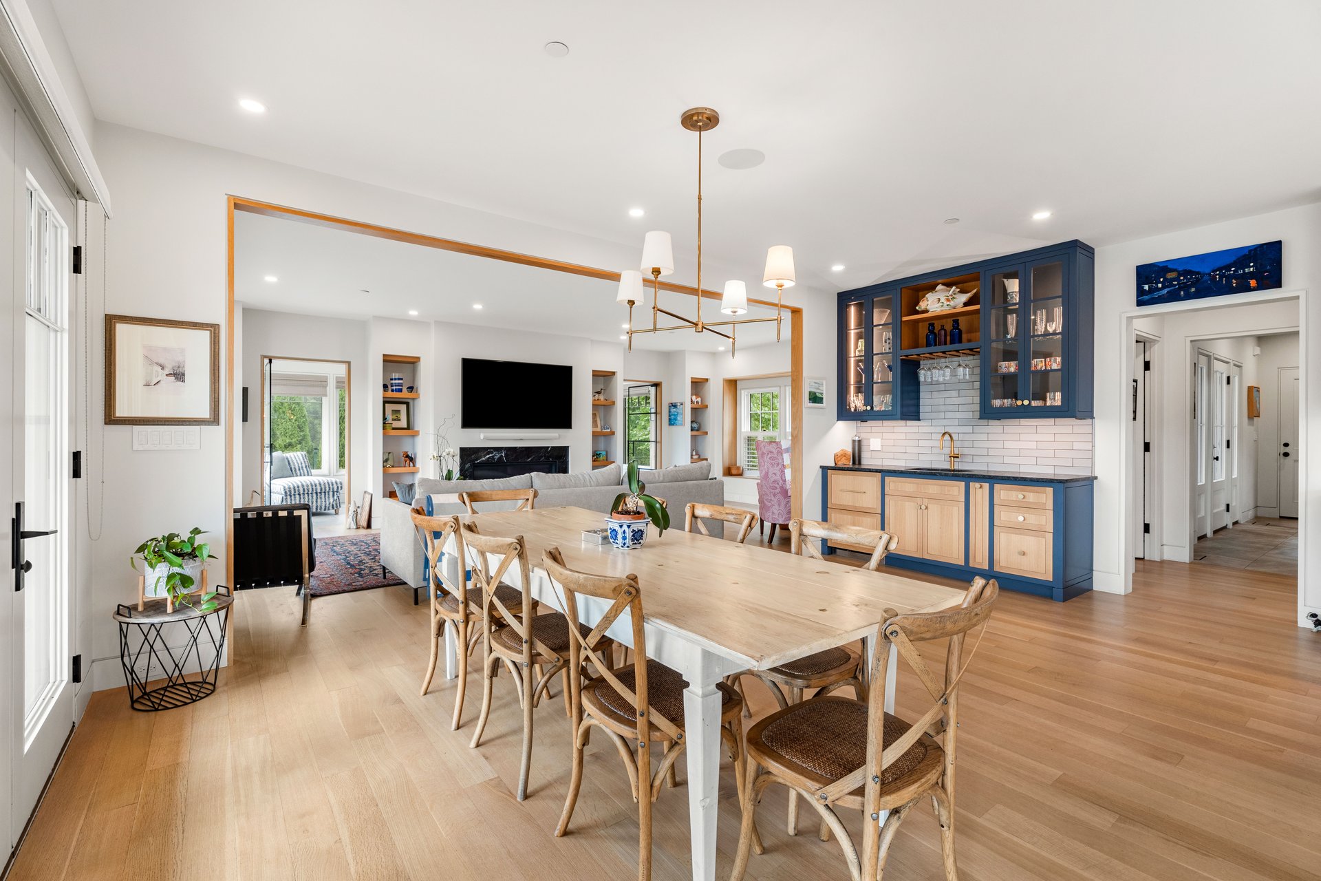 Open-plan dining room with a long wood table, blue kitchen cabinetry, and living room beyond.