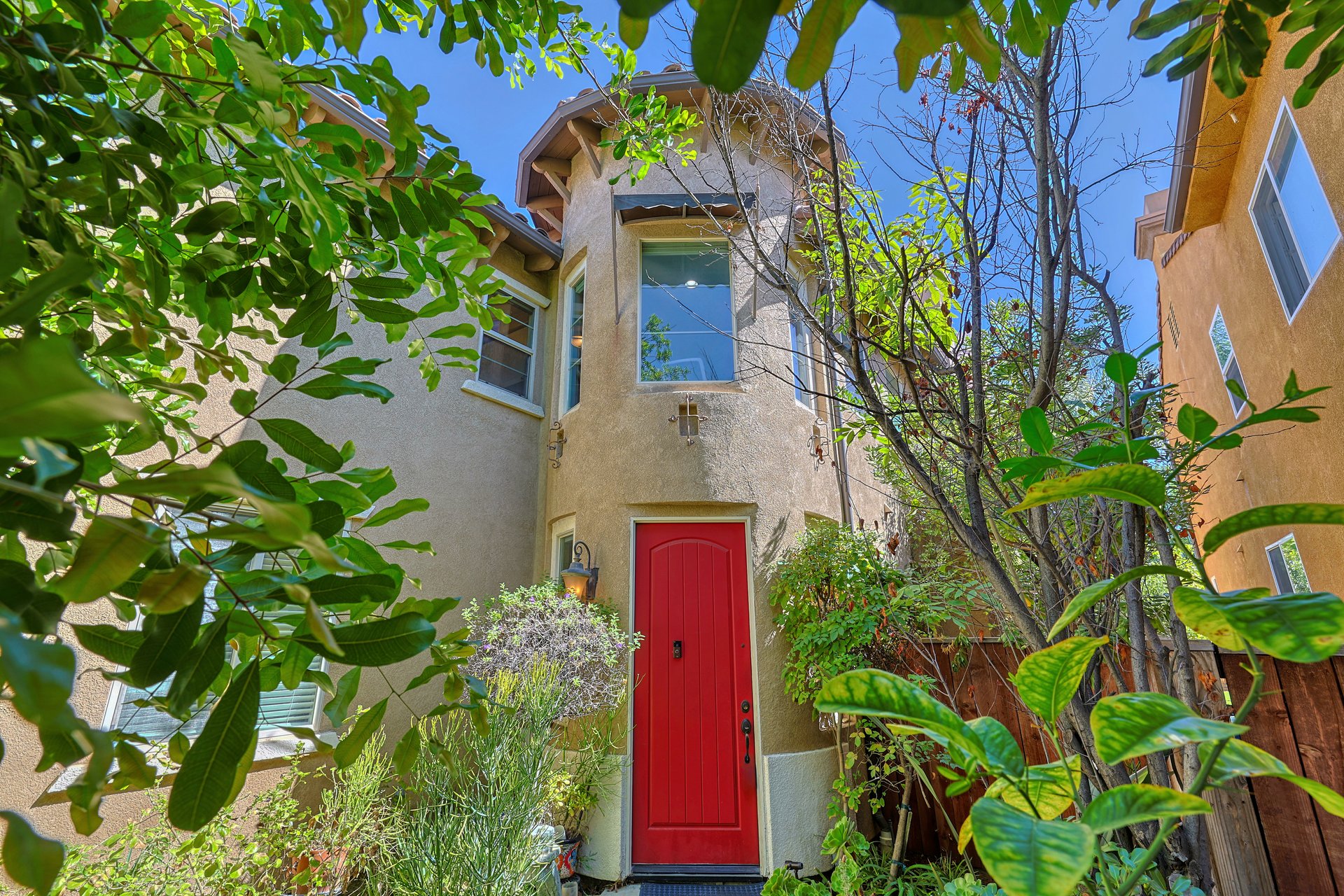 Front entrance with red door surrounded by mature landscaping