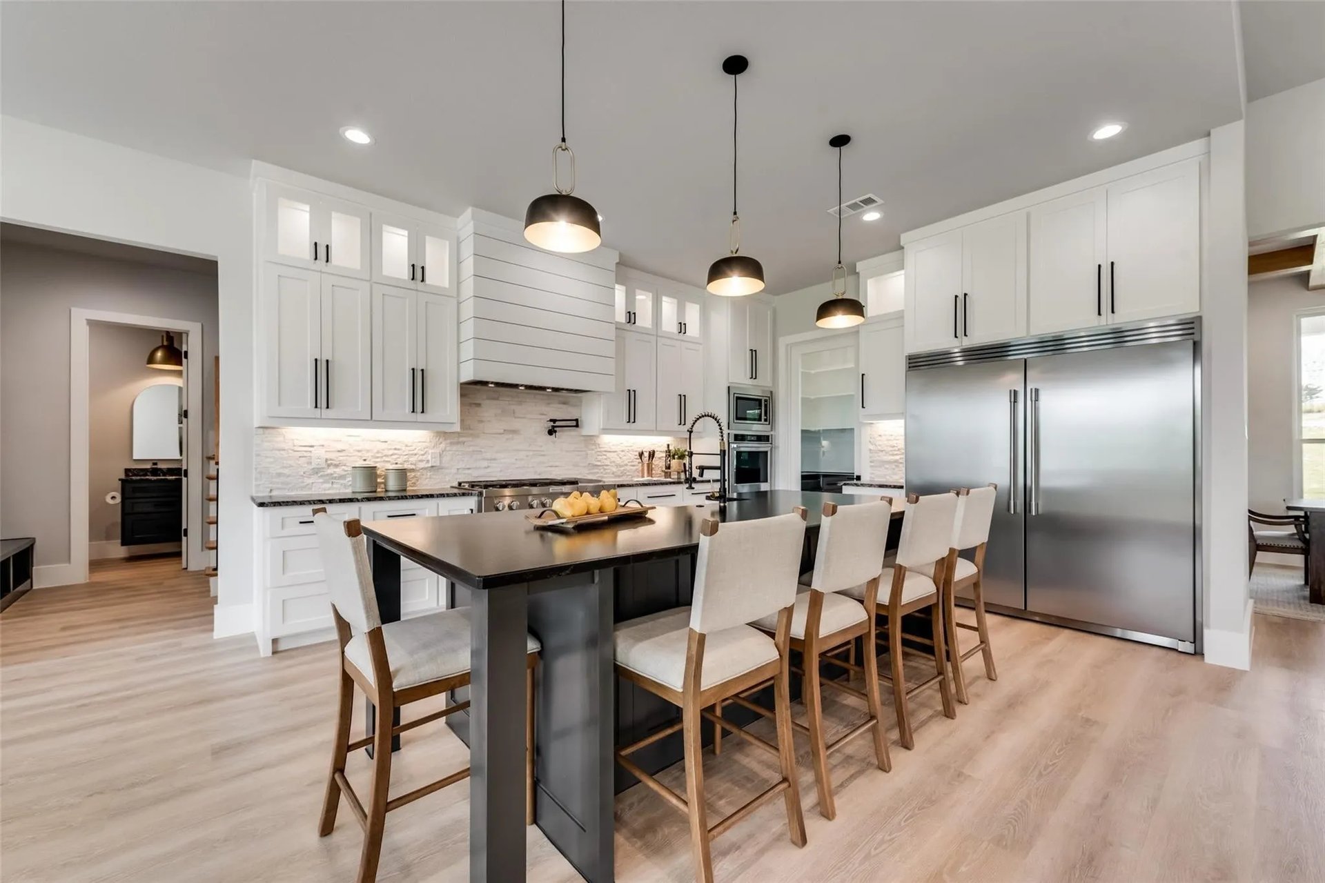 Bright kitchen with a large dark island, white cabinets, and stainless steel appliances.