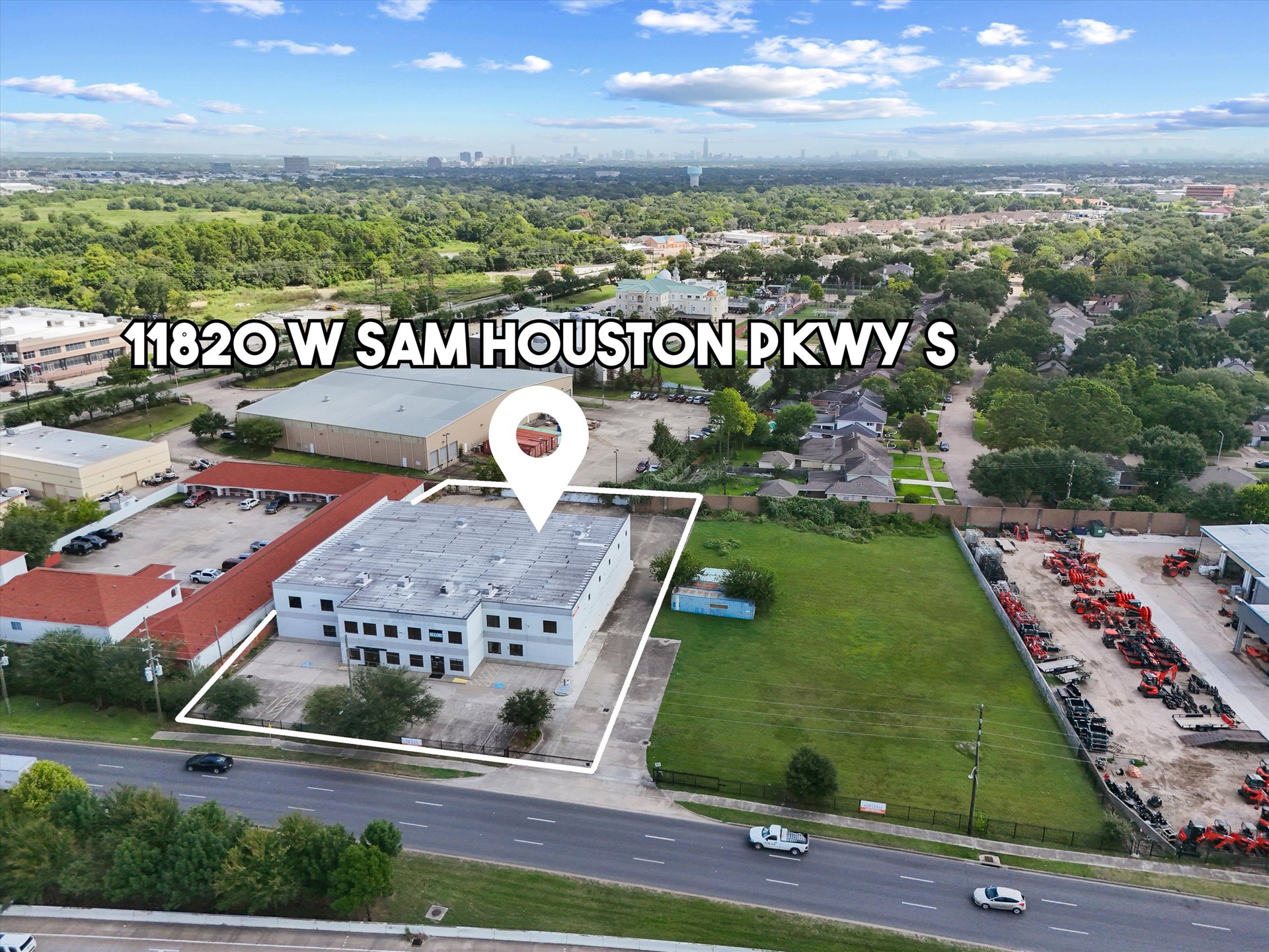 Aerial view of a two-story commercial building outlined beside a large grassy lot.