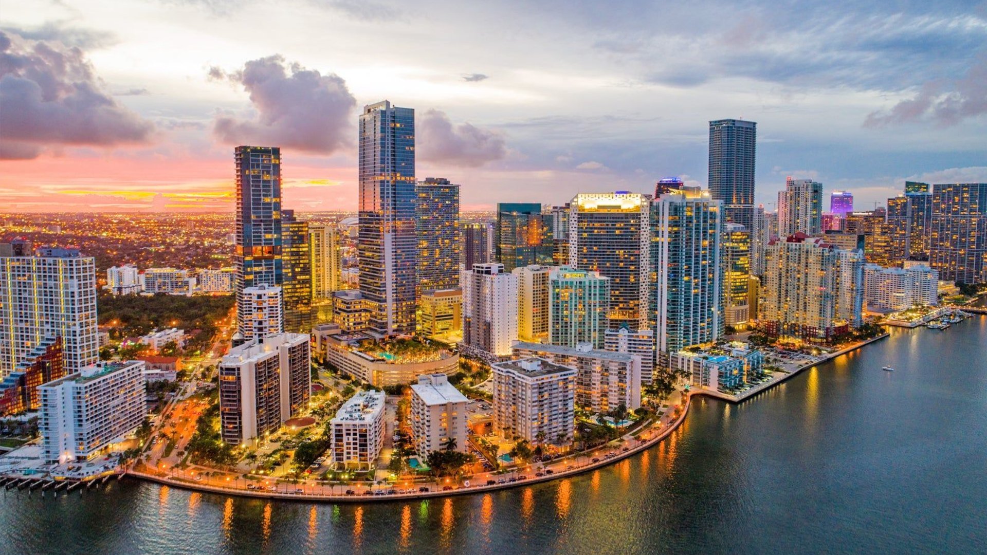 Aerial sunset view of Brickell Miami waterfront with high-rise buildings and Biscayne Bay - The Edit Real Estate