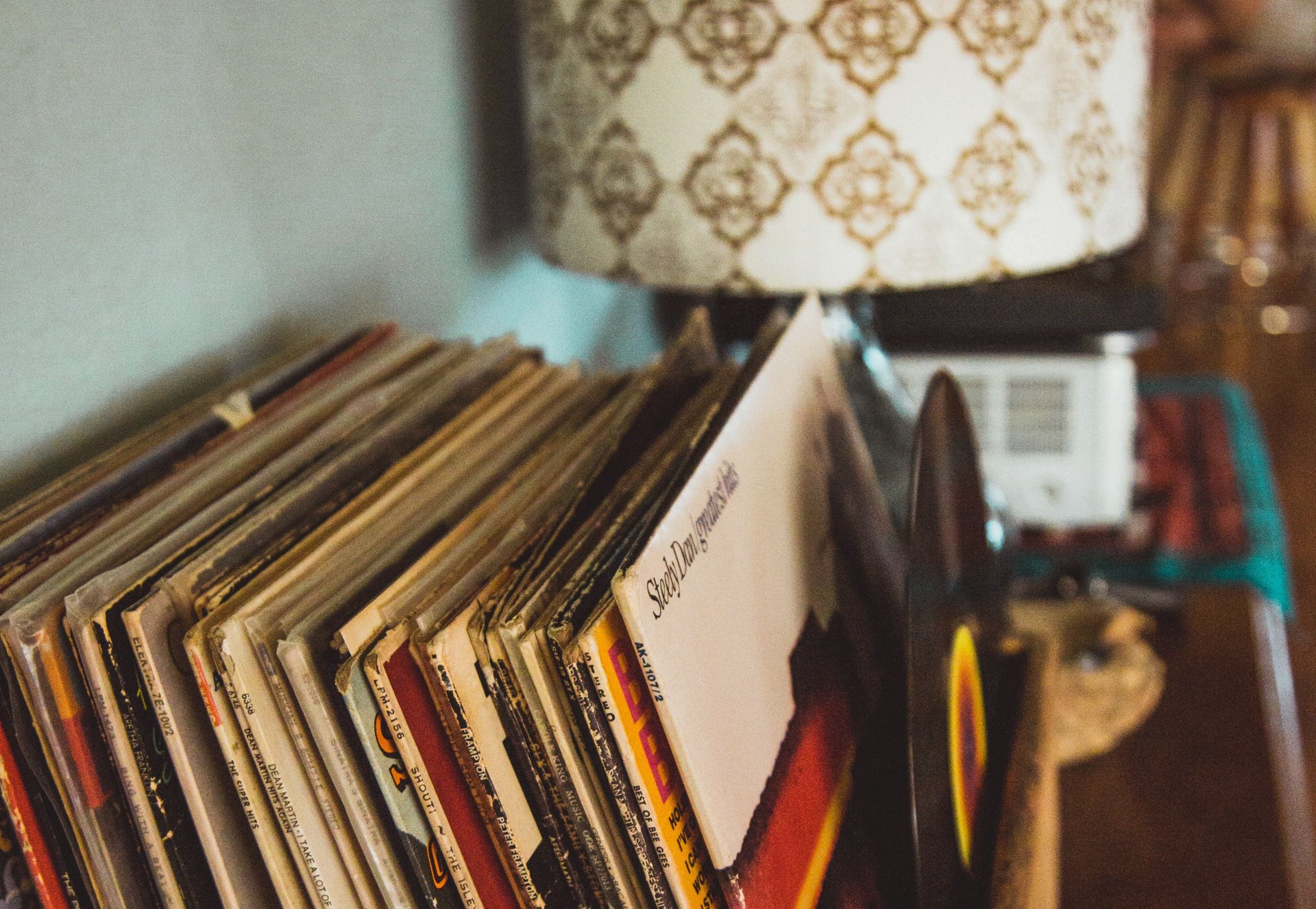 Vinyl records in a rack beside a glowing patterned table lamp.