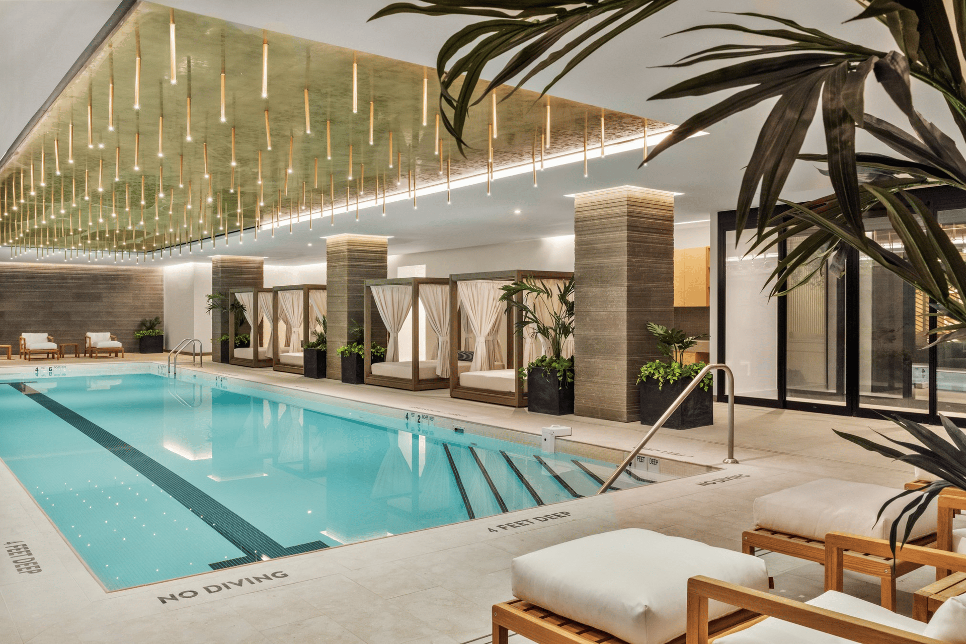 Indoor swimming pool with curtained cabanas and a ceiling of hanging lights.