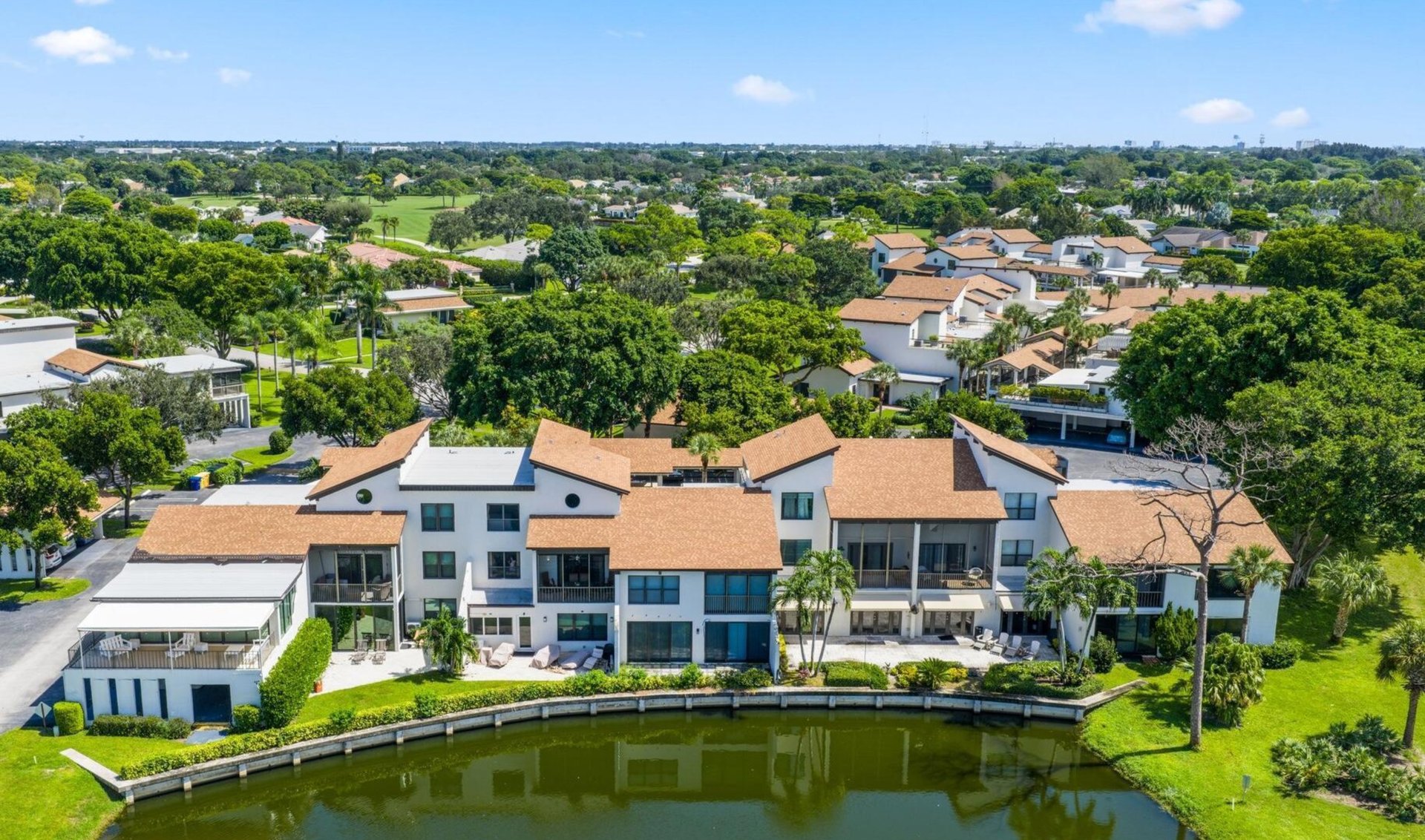 Aerial view of white homes with terracotta roofs lining a landscaped canal.