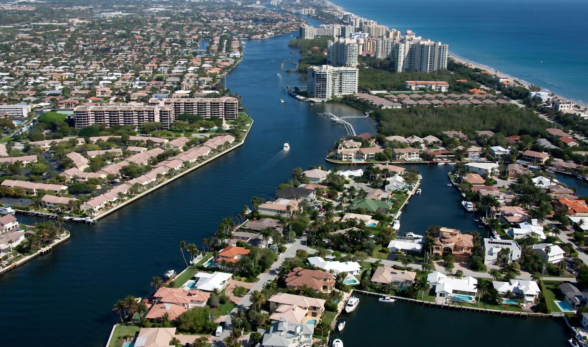 Aerial view of canal-front homes and docks, with oceanfront condominiums along the Atlantic coast.