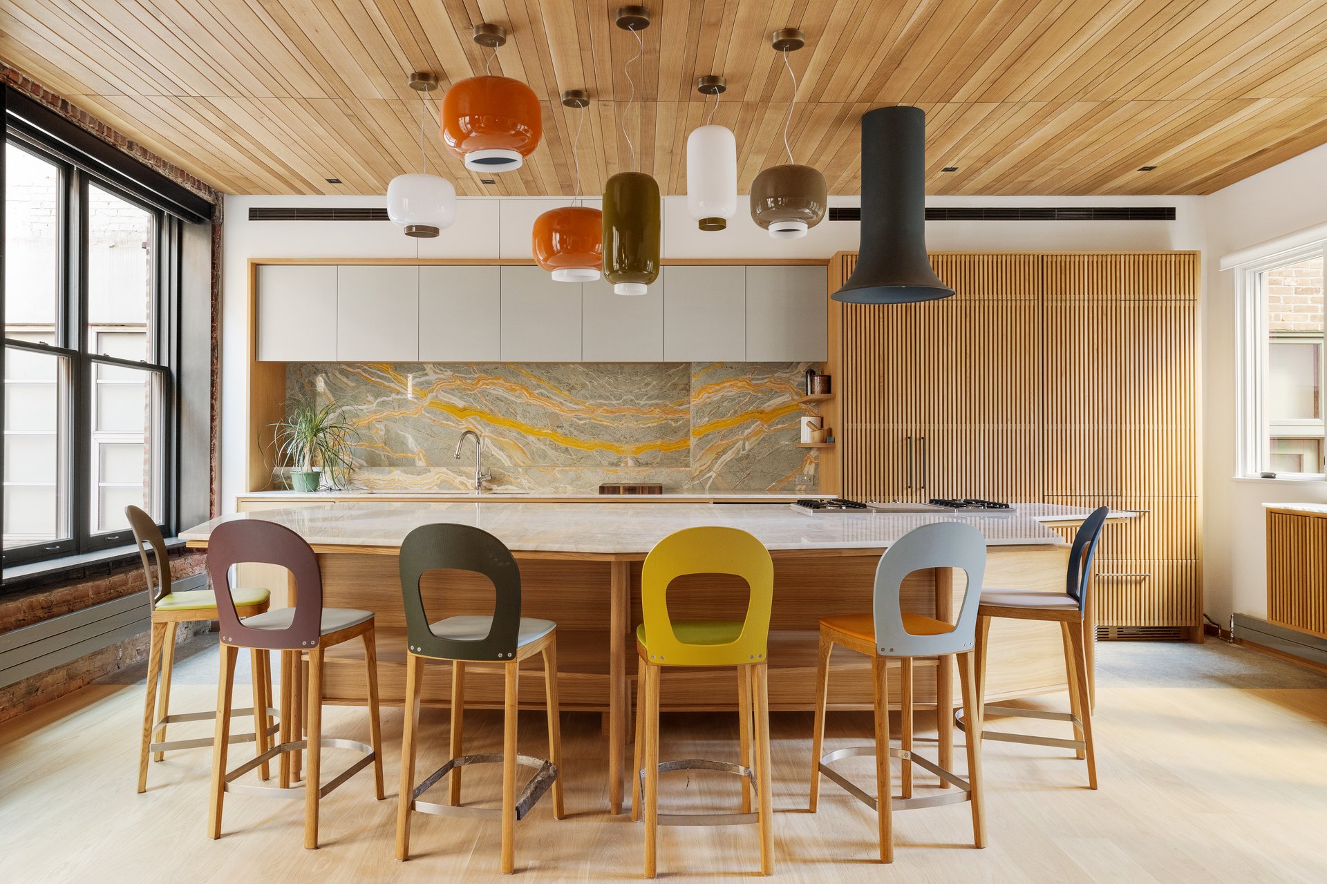 Kitchen and dining area at 50 Wooster Street 4NR, with an oak ceiling, pale stone island and veined stone backsplash.