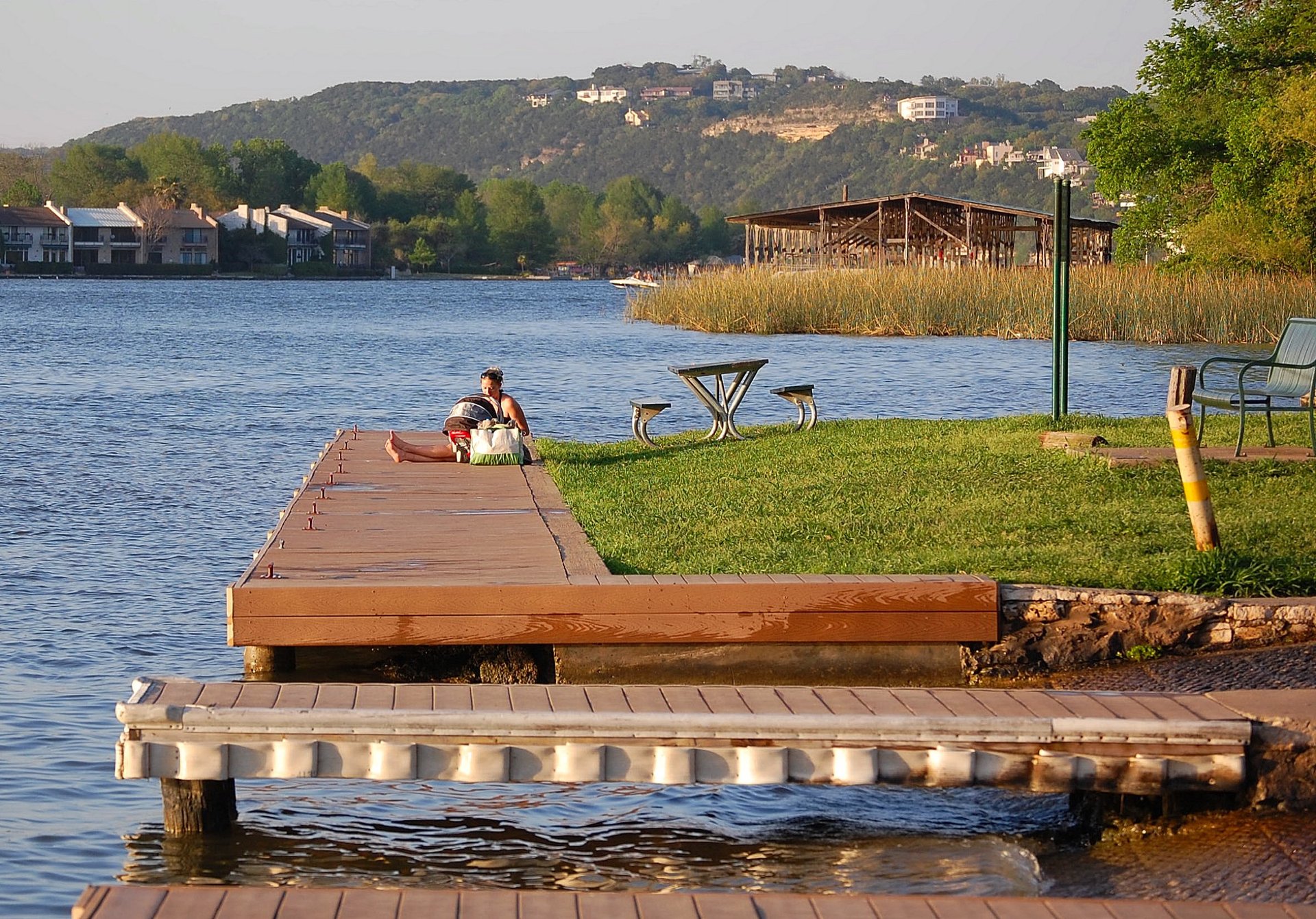 A wooden dock on Lake Austin in late afternoon light, Hill Country ridgeline behind.