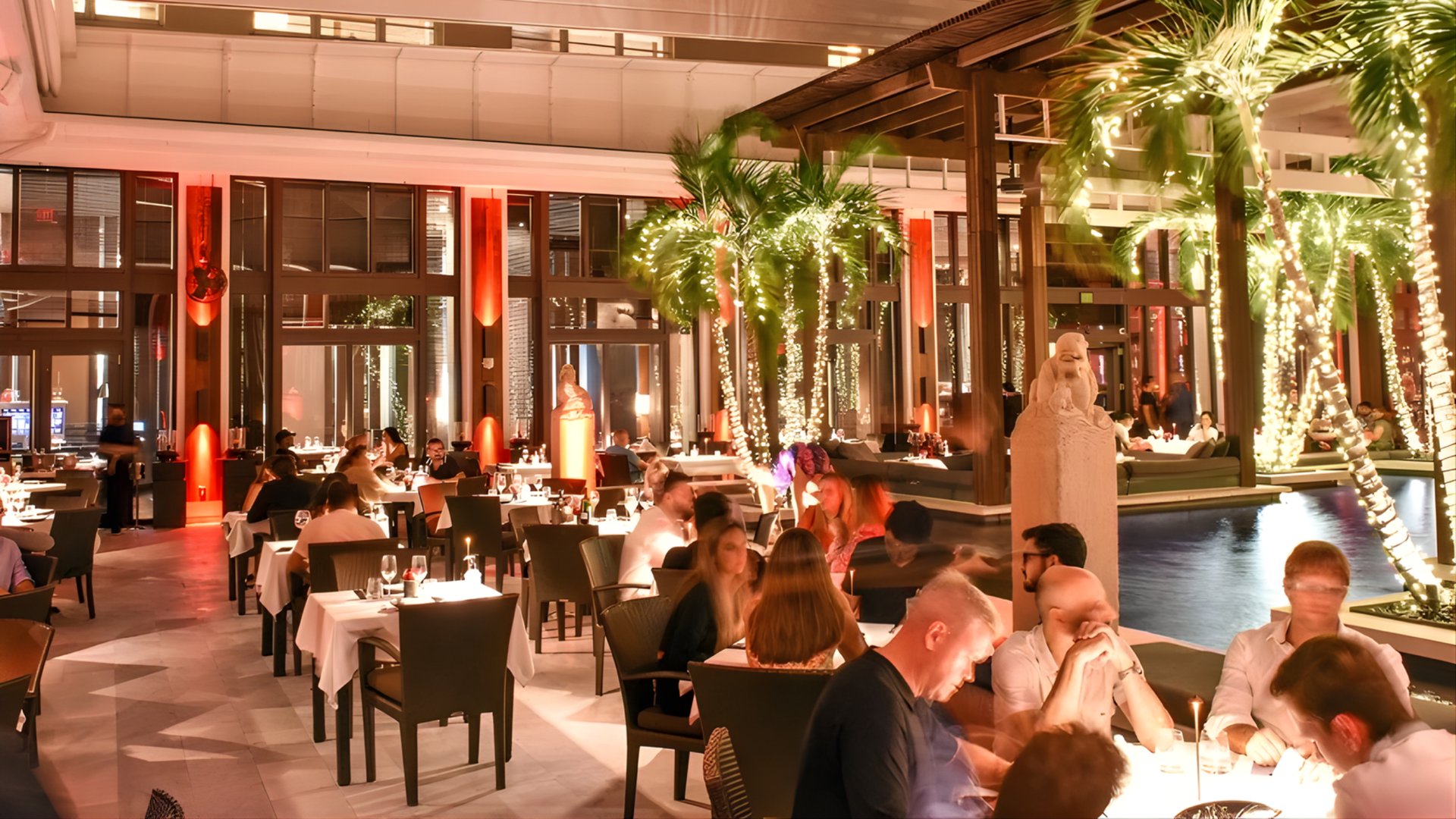 Upscale outdoor restaurant with festive lights, palm trees, and diners enjoying elegant ambiance for Thanksgiving in Miami by The Edit Real Estate