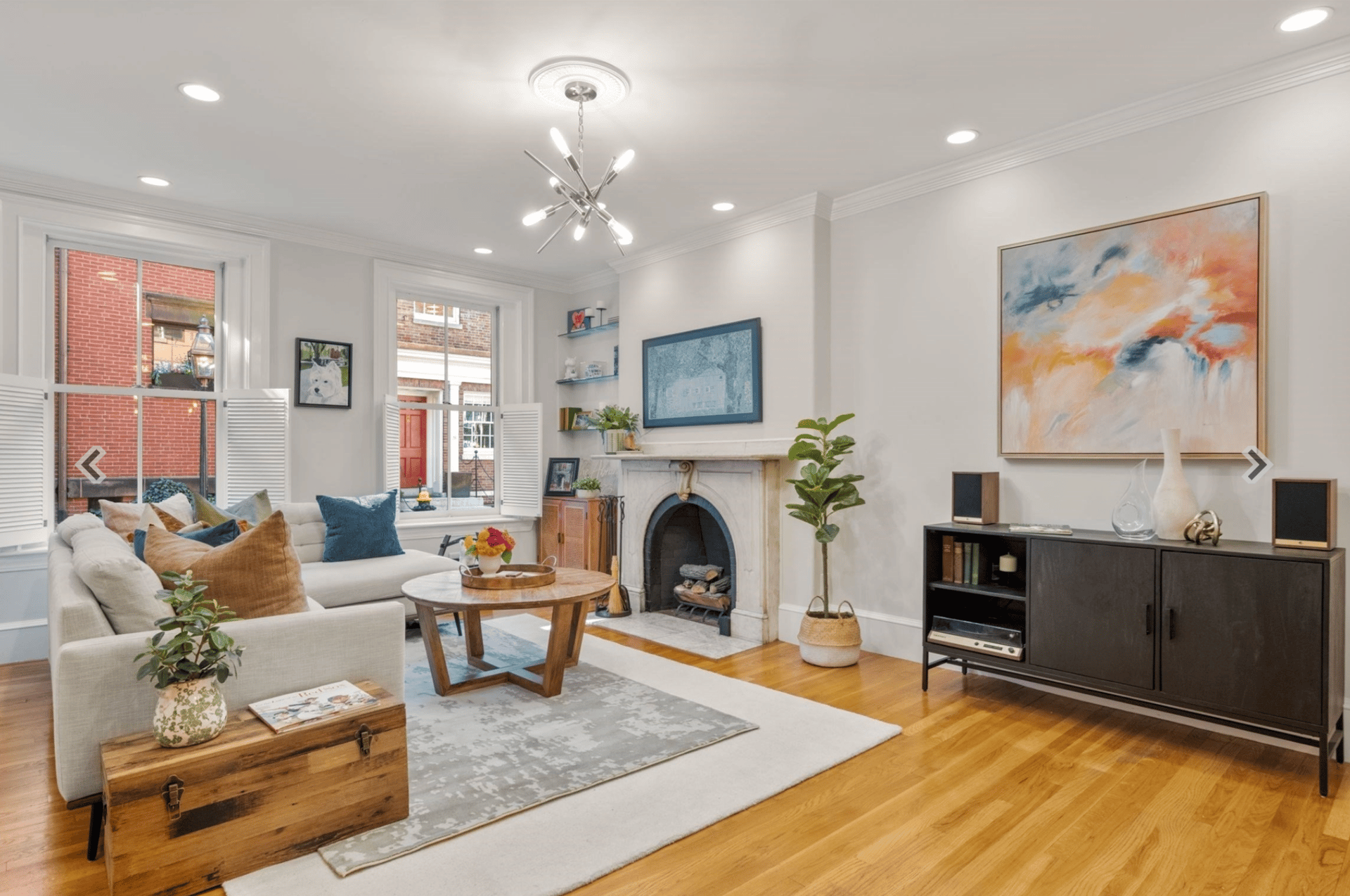 Living room with a marble fireplace, shuttered windows, and a cream sofa.