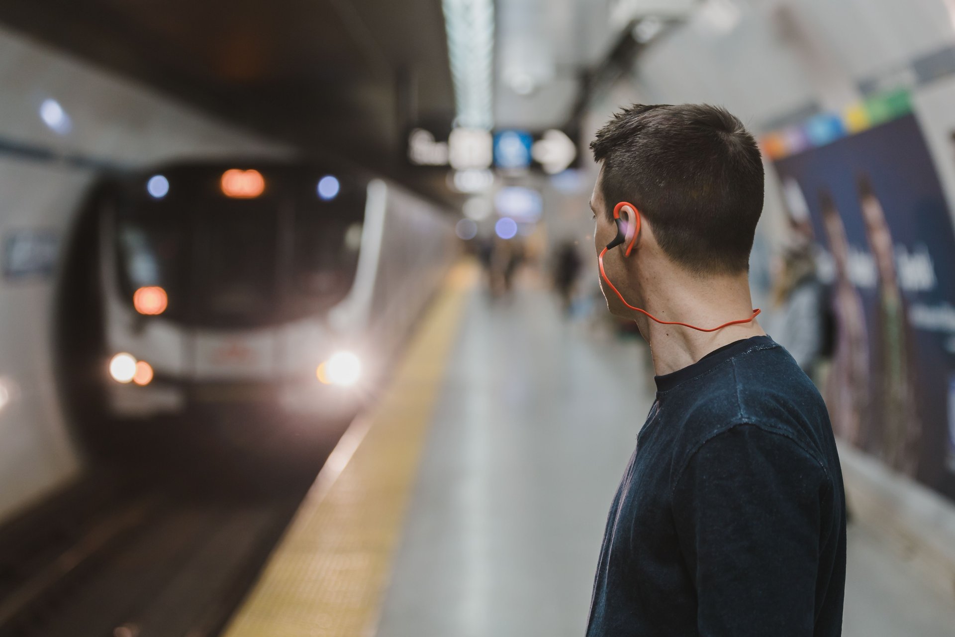 a man in a train station with earphones on his ear