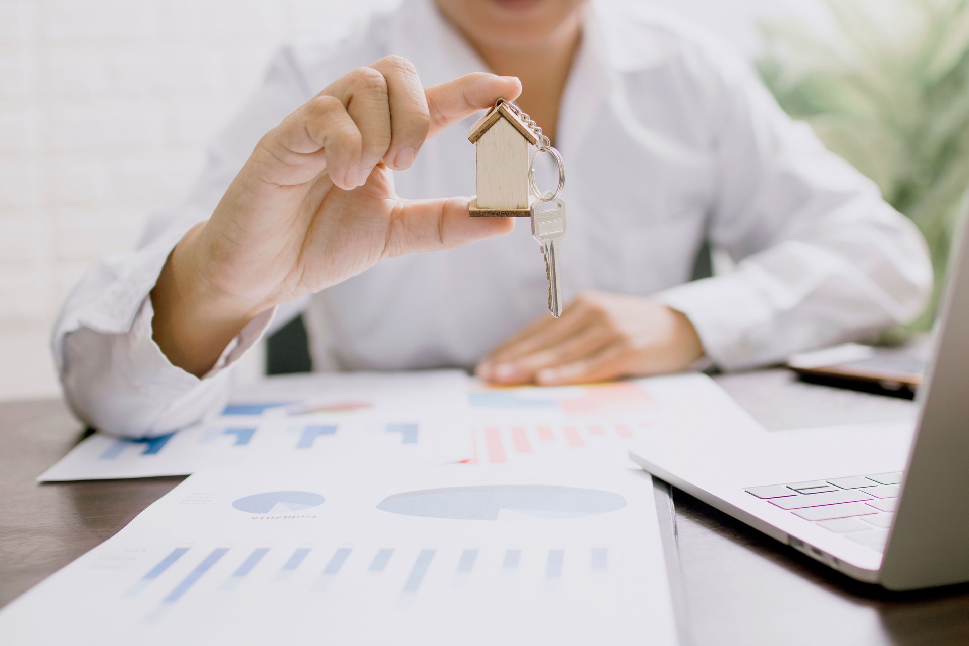a person in long sleeve shirt holding a house keychain with a key
