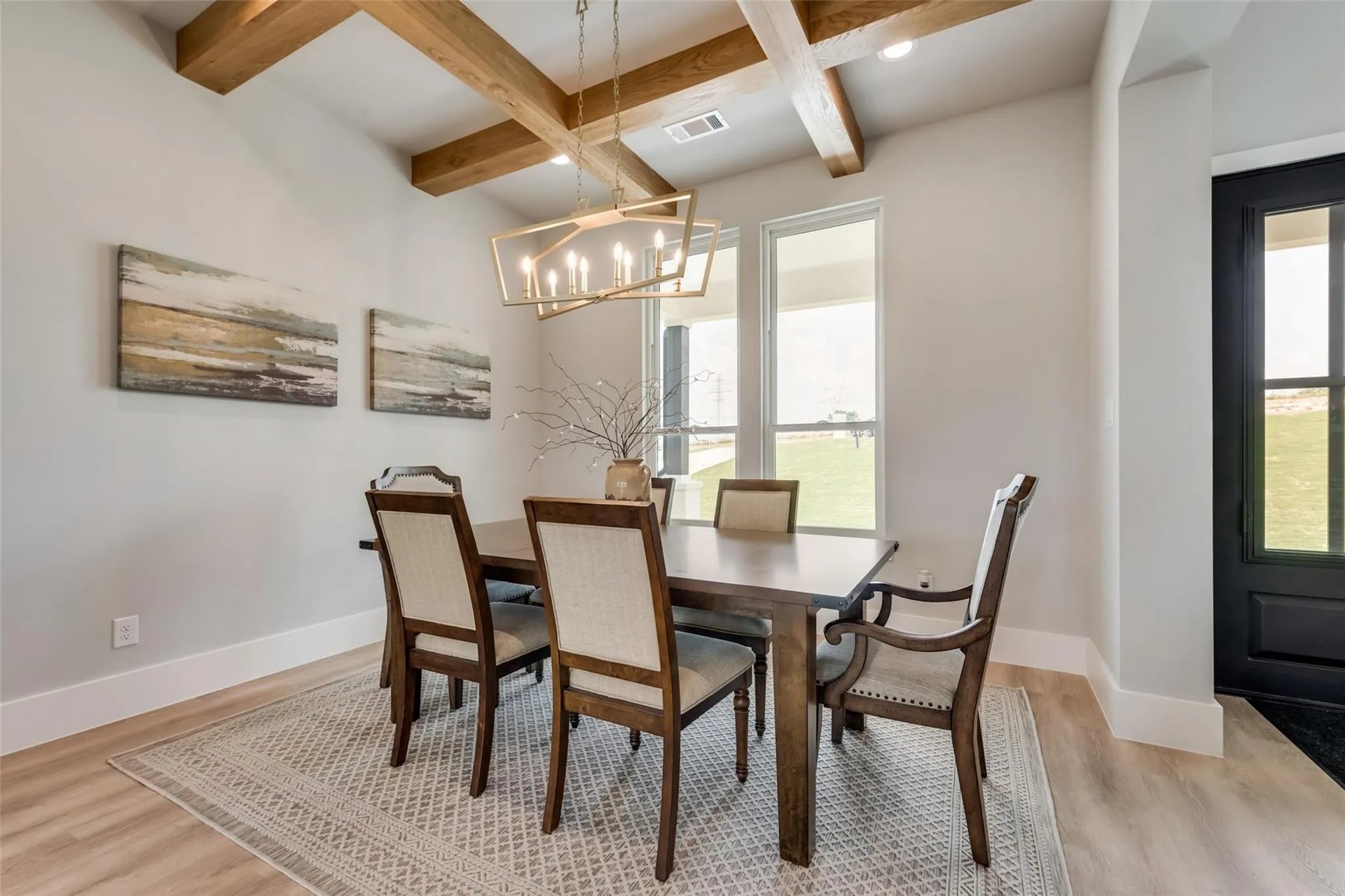 Dining room with exposed timber ceiling beams, a geometric chandelier, and a dark wood table.