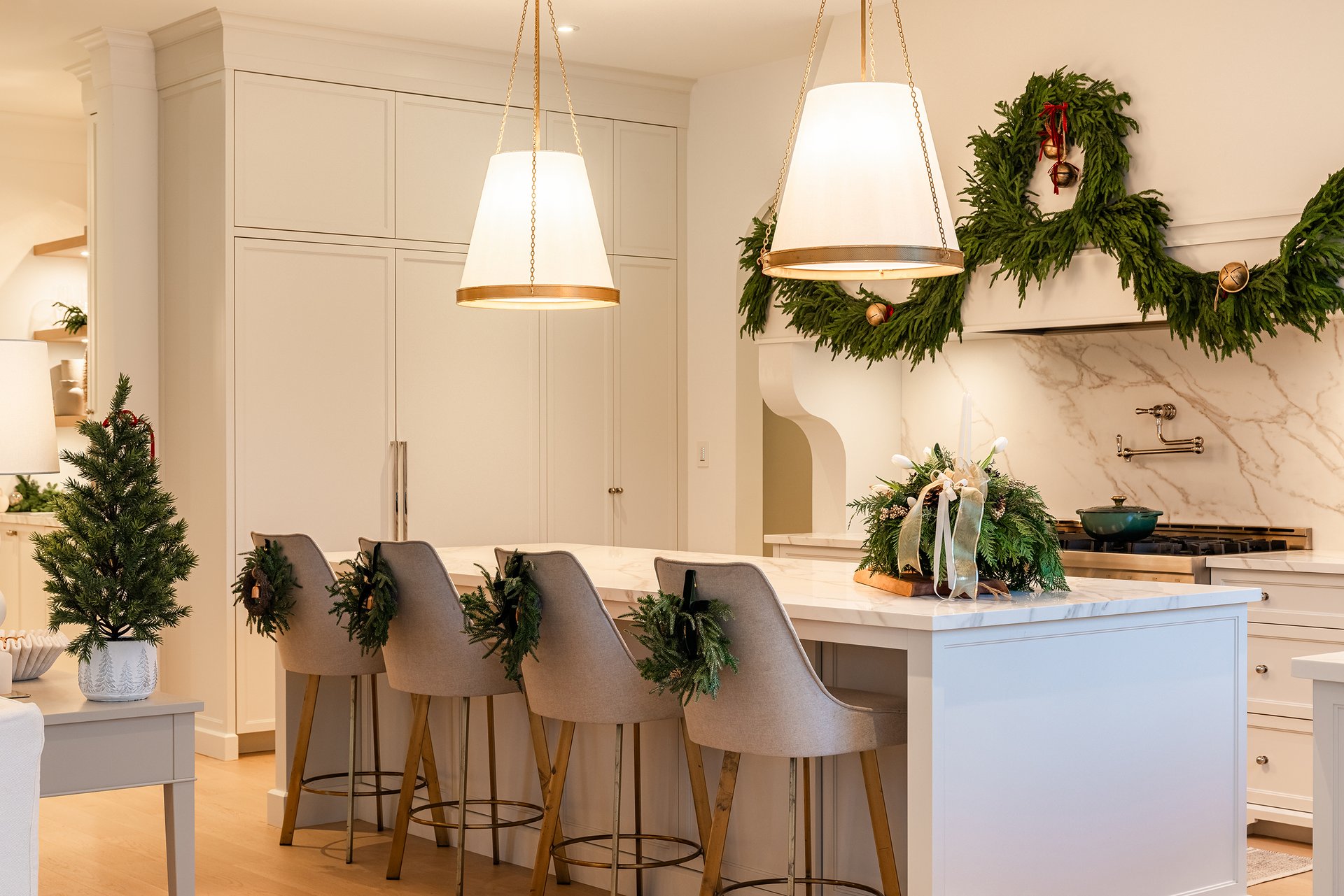 Warm Christmas kitchen d&eacute;cor in an Oakville custom home with marble counters, garland, and a peek into a children&rsquo;s playroom decorated for the holidays.
