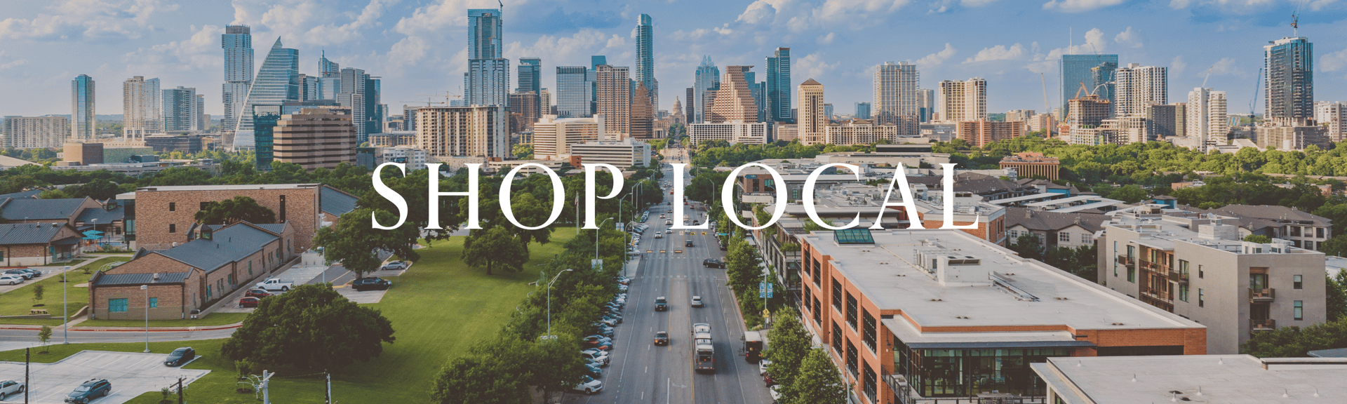 Aerial view of a city skyline with modern buildings, greenery, and a street. Text overlay: "SHOP LOCAL."