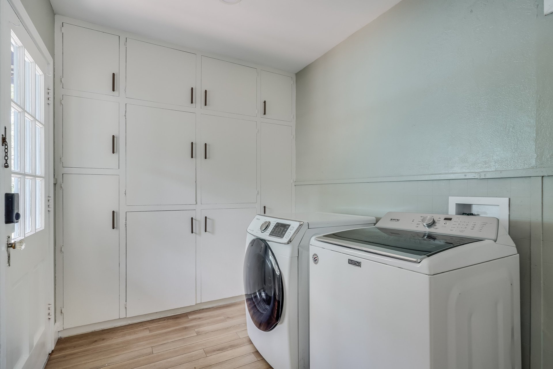 Laundry room with white washer and dryer beside extensive built-in storage cabinets.