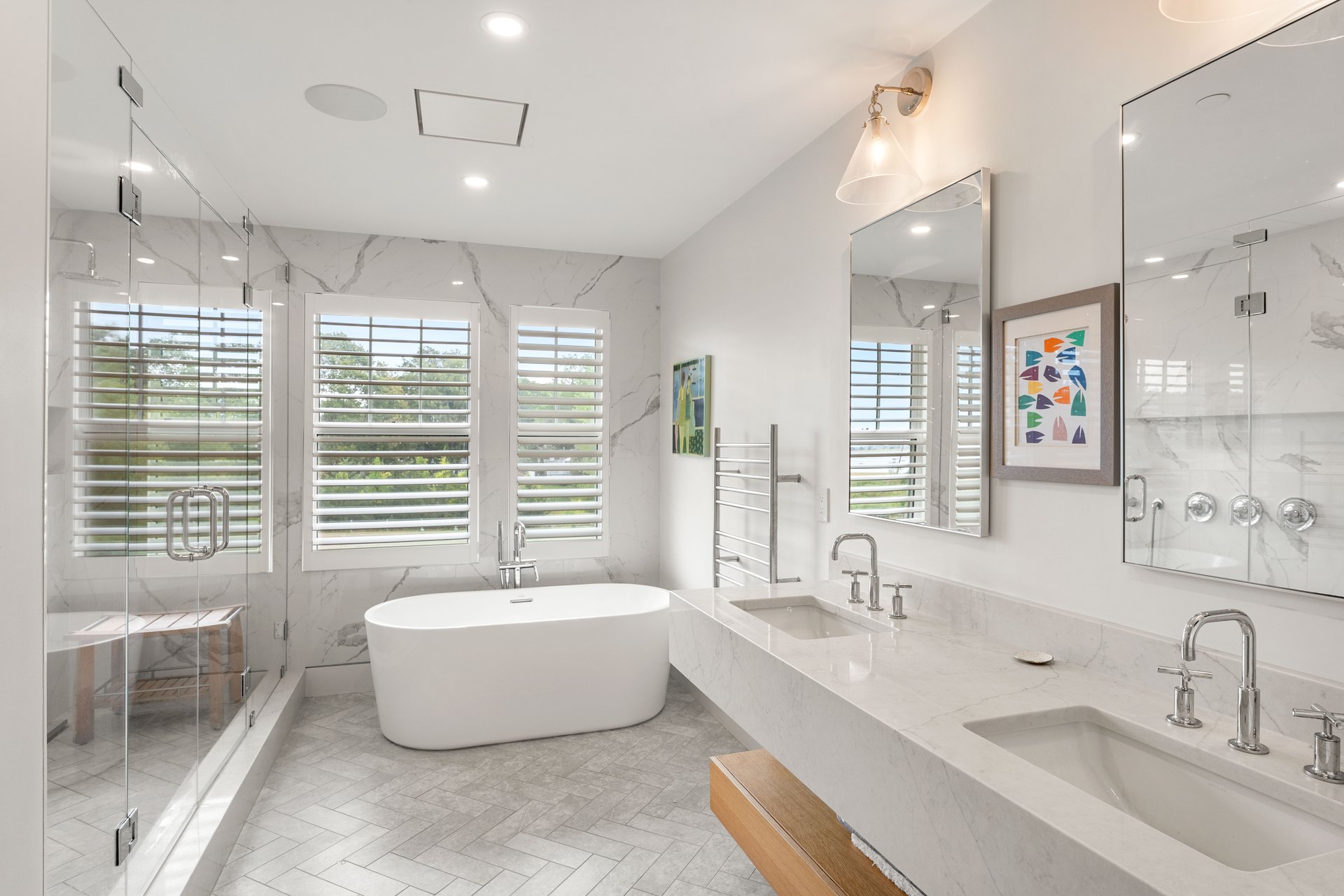 Modern bathroom with a freestanding tub, glass shower, and marble-look double vanity.