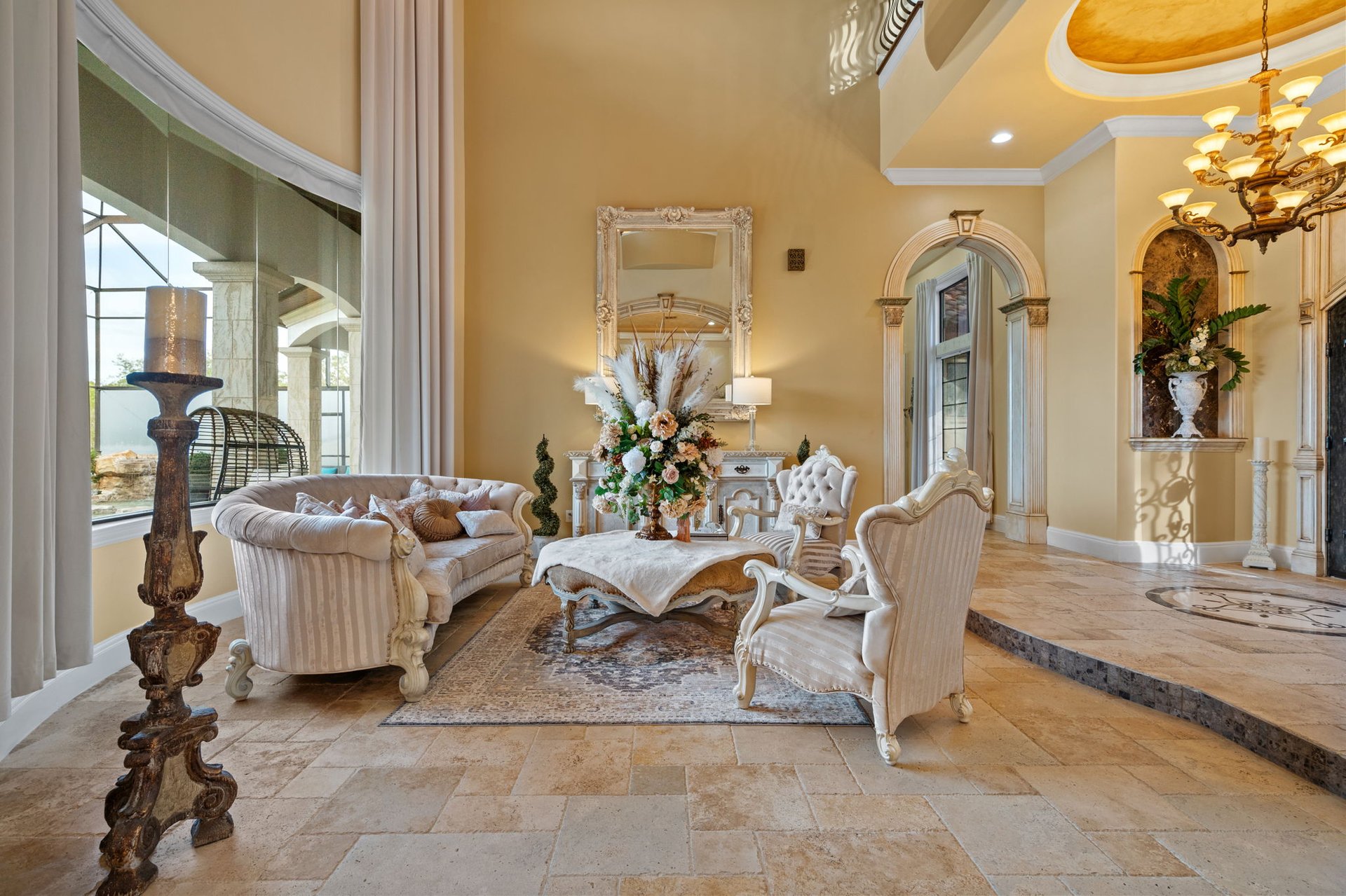 Formal sitting room with cream seating, arched details, and a chandelier.