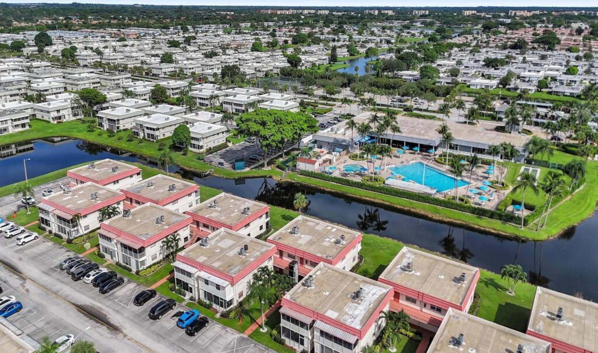 Aerial view of a residential community with a swimming pool, clubhouse, and canal.