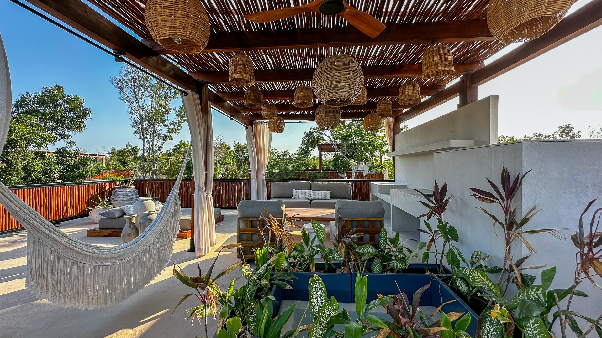 Rooftop terrace with a wood-slat pergola, woven lights, hammock, and outdoor lounge seating.
