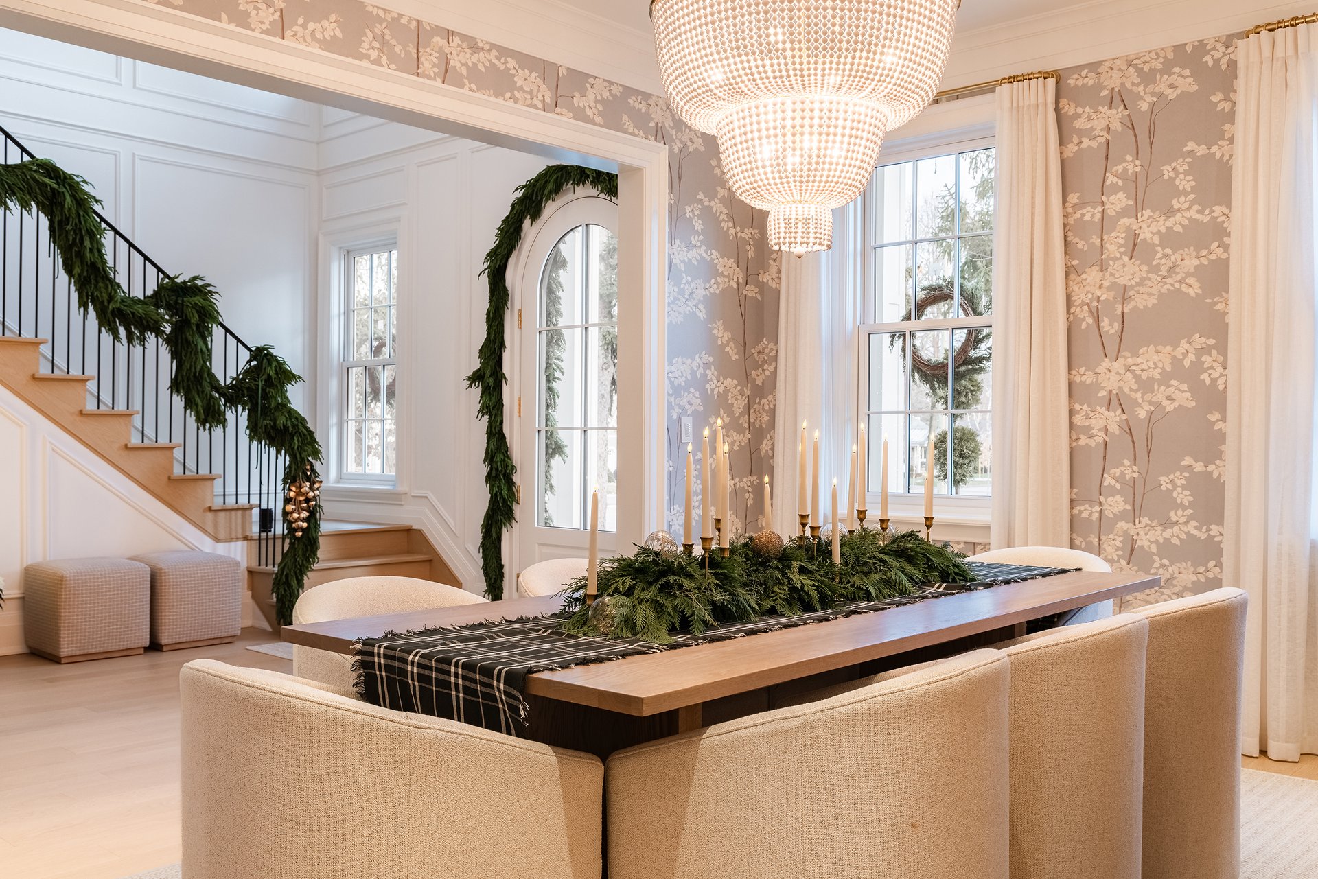 Dining room in an Oakville custom home with holiday table greenery and a view toward the entryway staircase with natural garland.