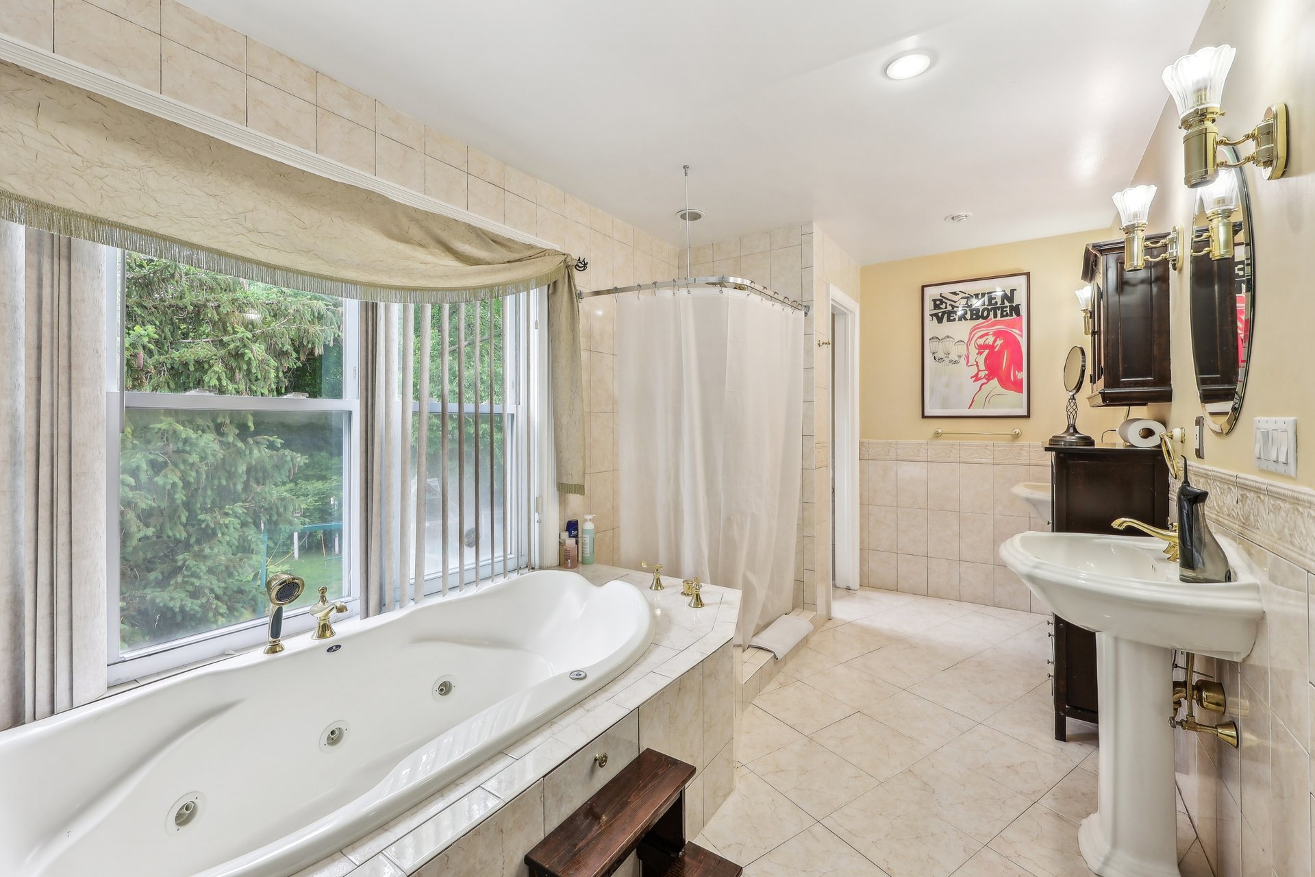 Tiled bathroom with a jetted tub beneath a large window and a separate shower.