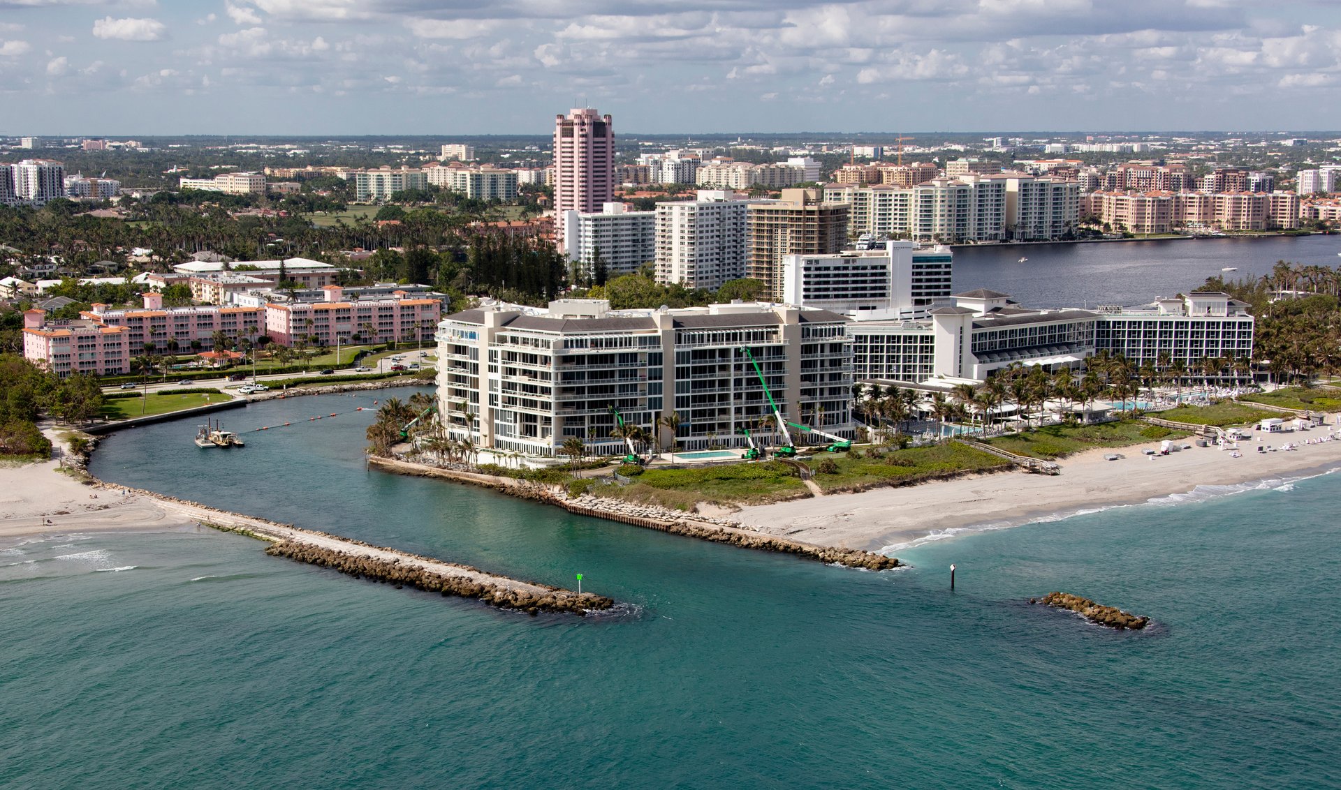 Aerial view of coastal high-rises beside an inlet, beach and turquoise ocean.