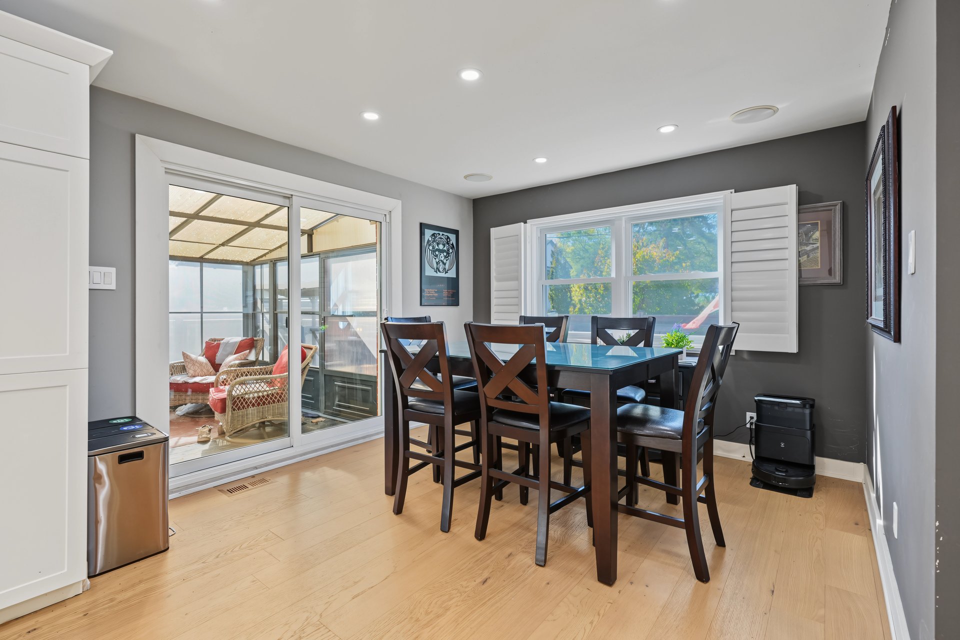 Dining room with a dark wood table beside sliding glass doors to an enclosed sunroom.