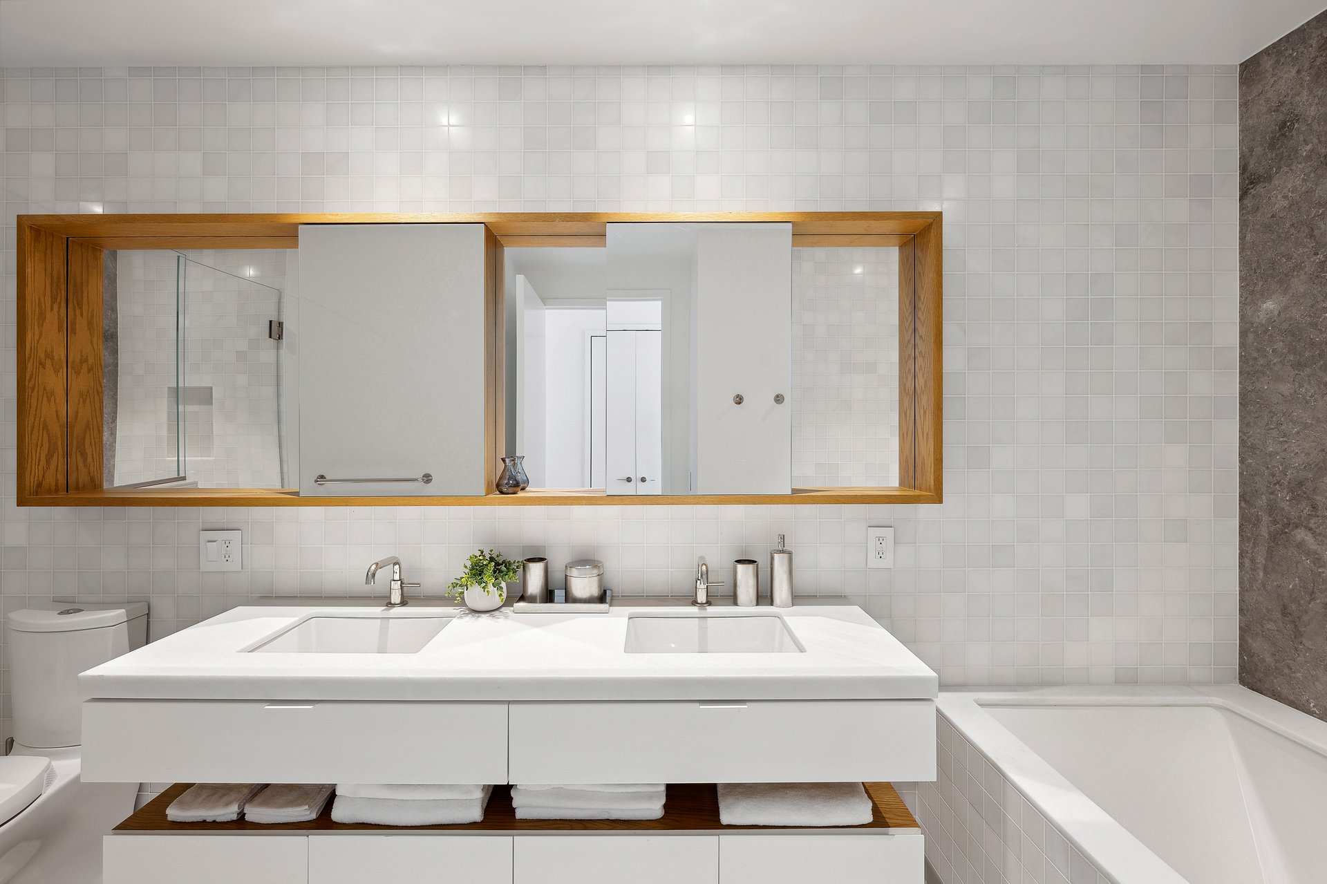Bathroom with a double-sink vanity, wood-framed mirrors, and a bathtub.