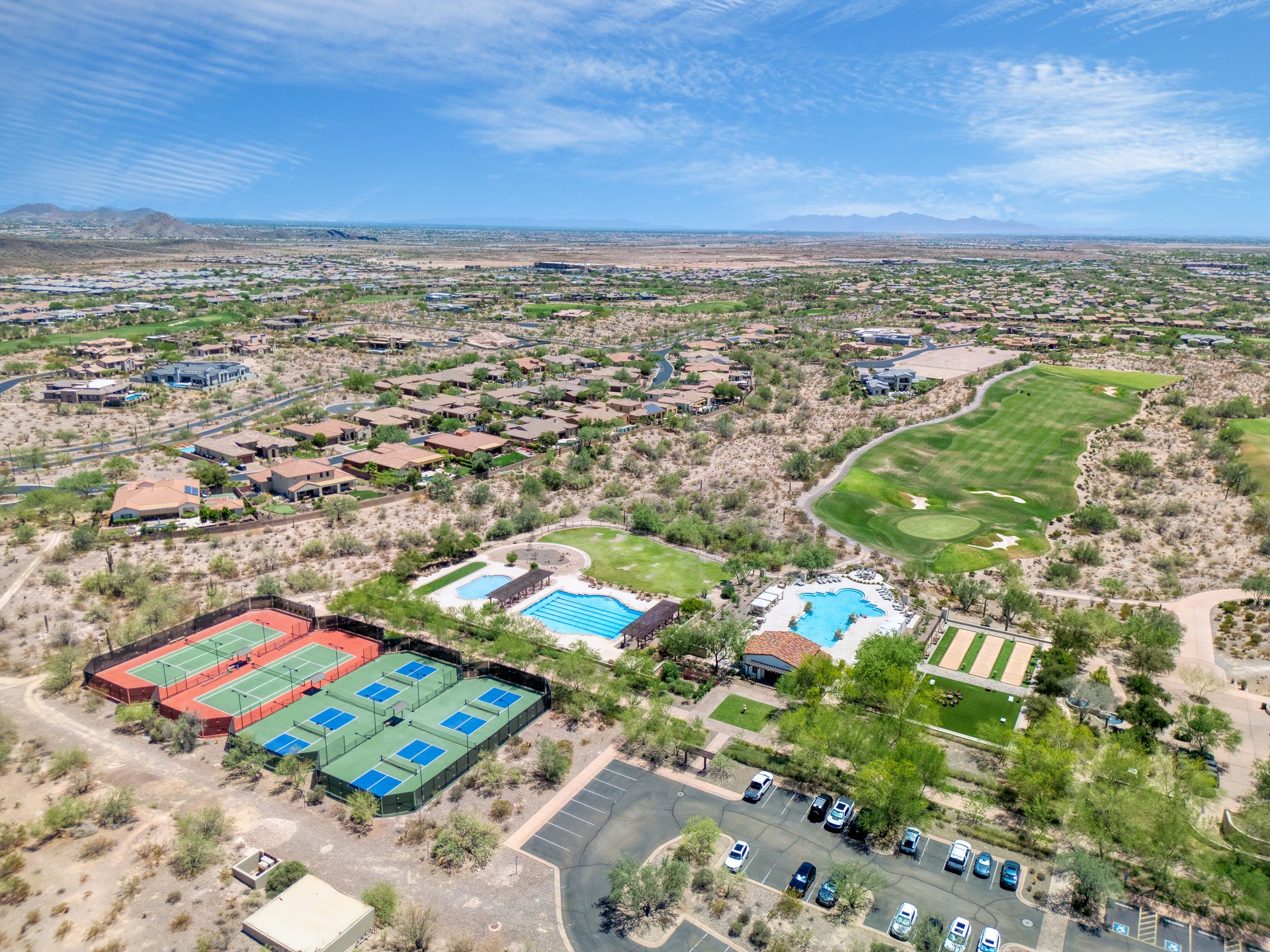 Aerial view of the neighborhood around 30959 North 120th Ave, with a golf course, tennis courts, swimming pools, and homes across the desert landscape.