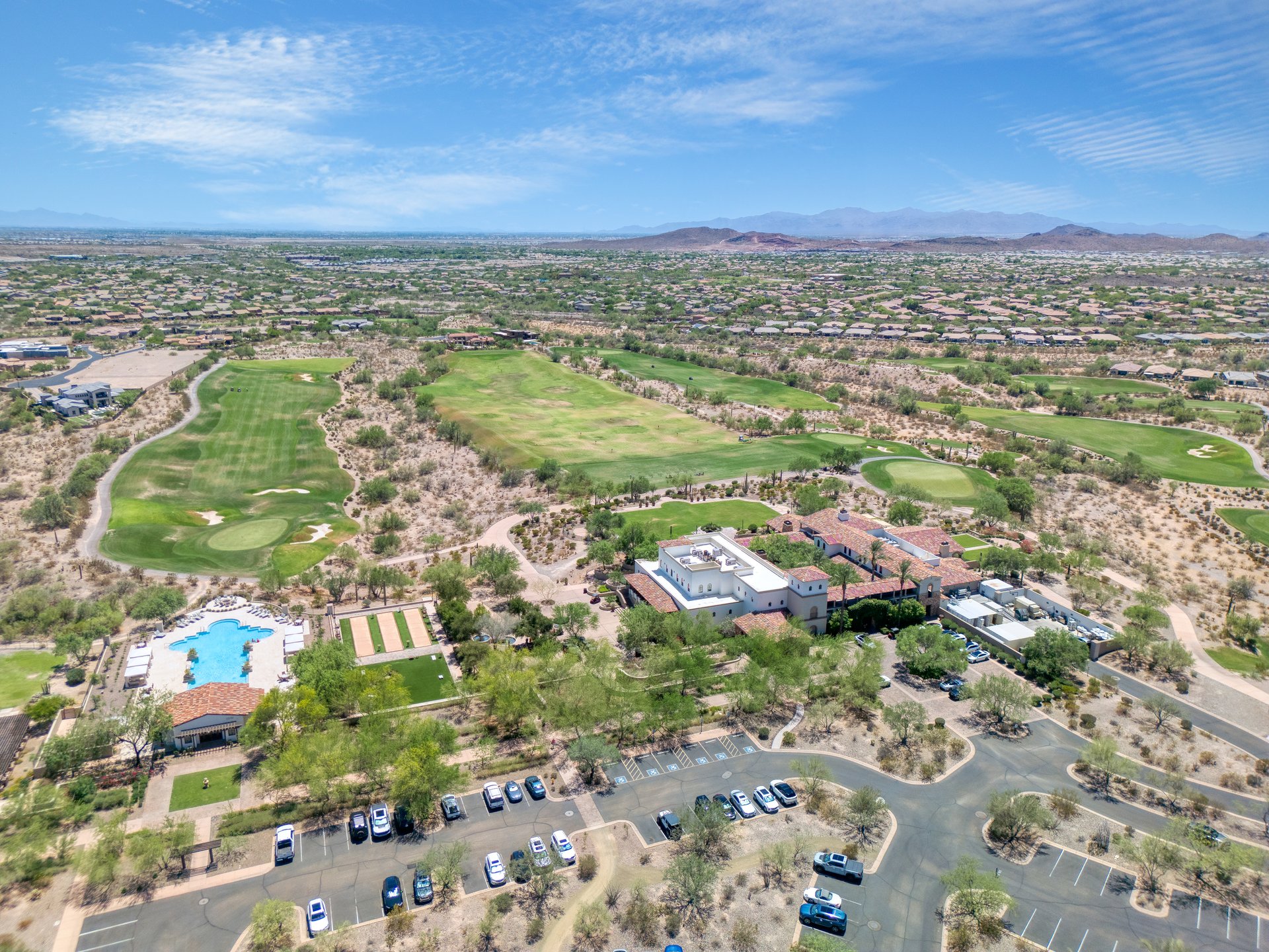 Aerial view of 30959 North 120th Avenue, with golf course greens, buildings, a swimming pool and parking areas amid desert neighborhoods.