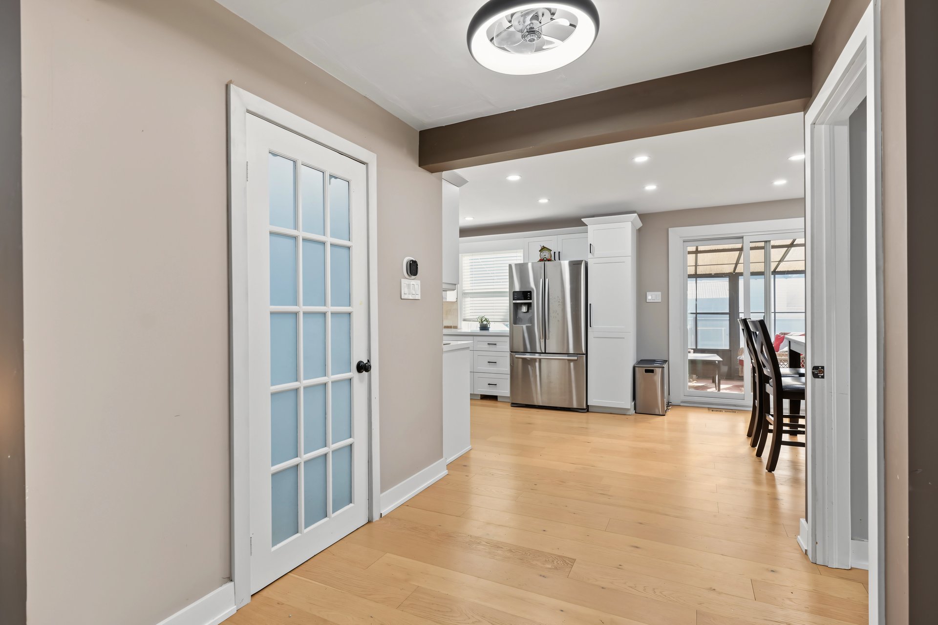 Kitchen and dining area with stainless steel refrigerator, light wood floors, and sliding doors to a covered patio.