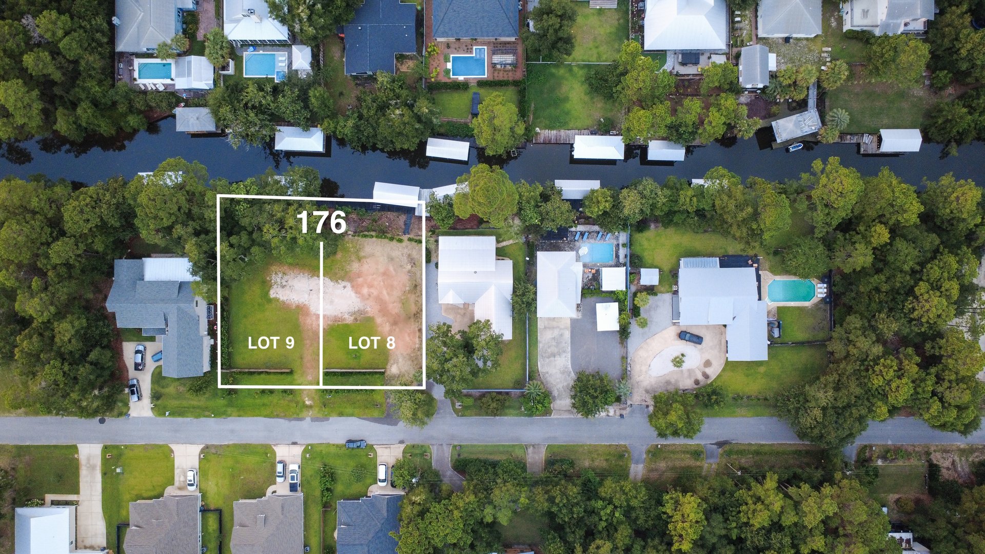 Aerial view of waterfront lots 8 and 9, outlined beside a canal and neighboring homes.