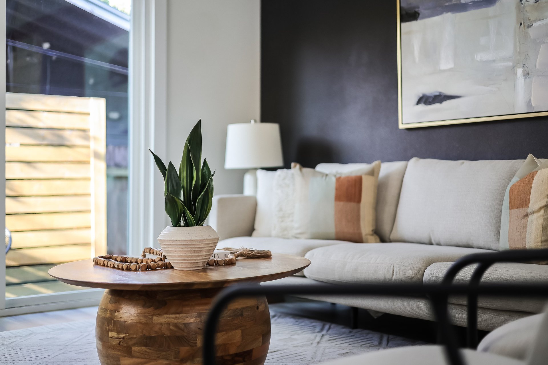 Living room with a cream sofa, round wooden coffee table, and potted plant.