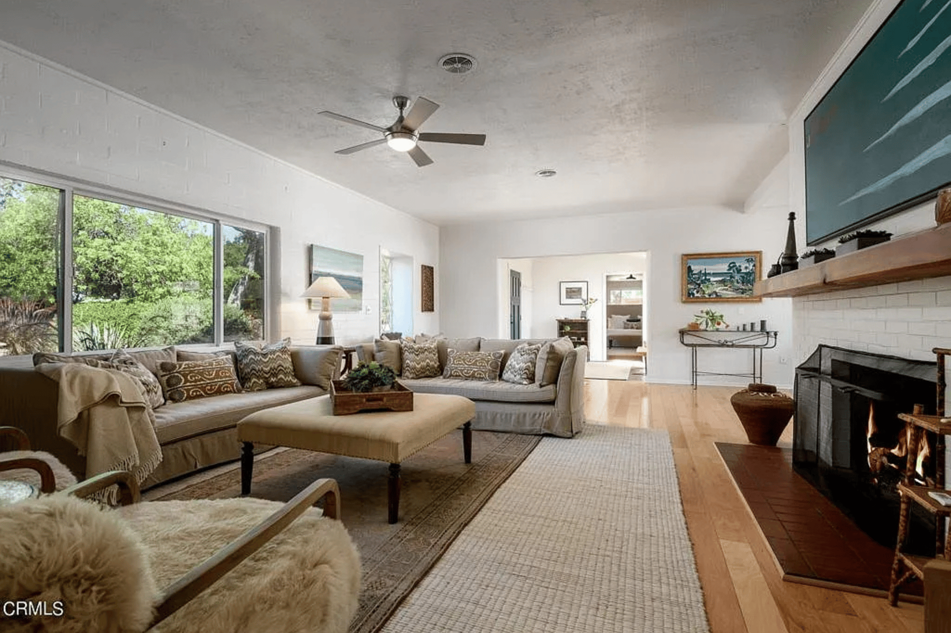 Living room with a sectional sofa, garden-facing windows, and a lit fireplace.