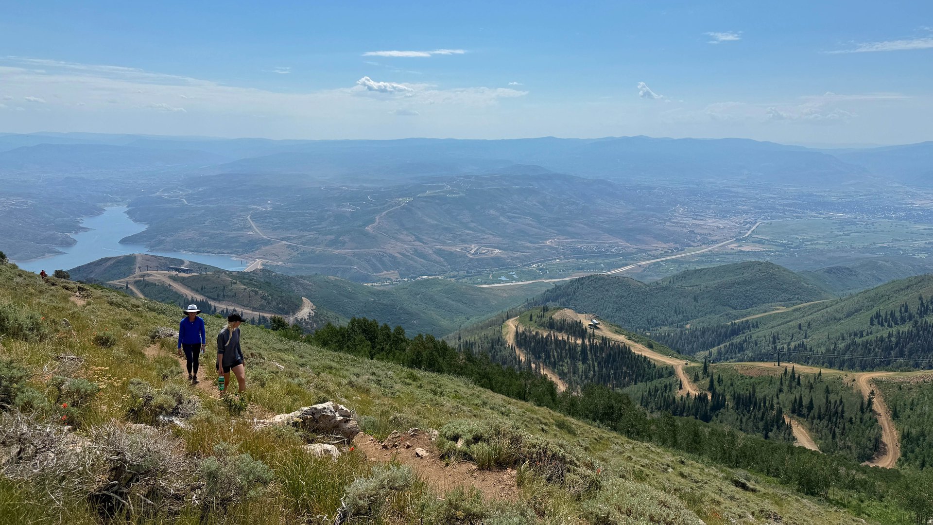 two hikers on a trail with views of mountains and reservoir
