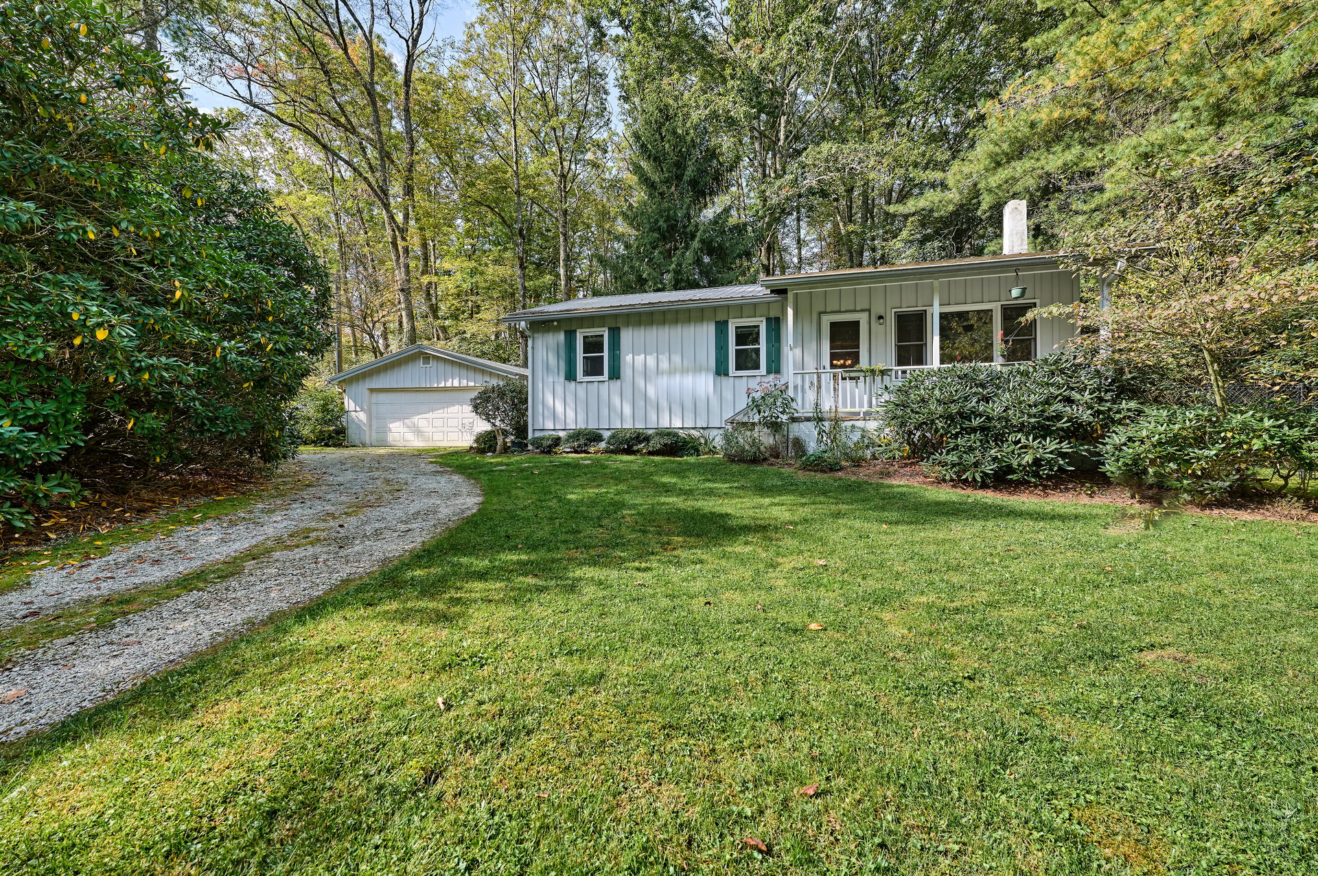 White cottage with green shutters, a front porch and detached garage at 556 Shortoff Road, Highlands NC