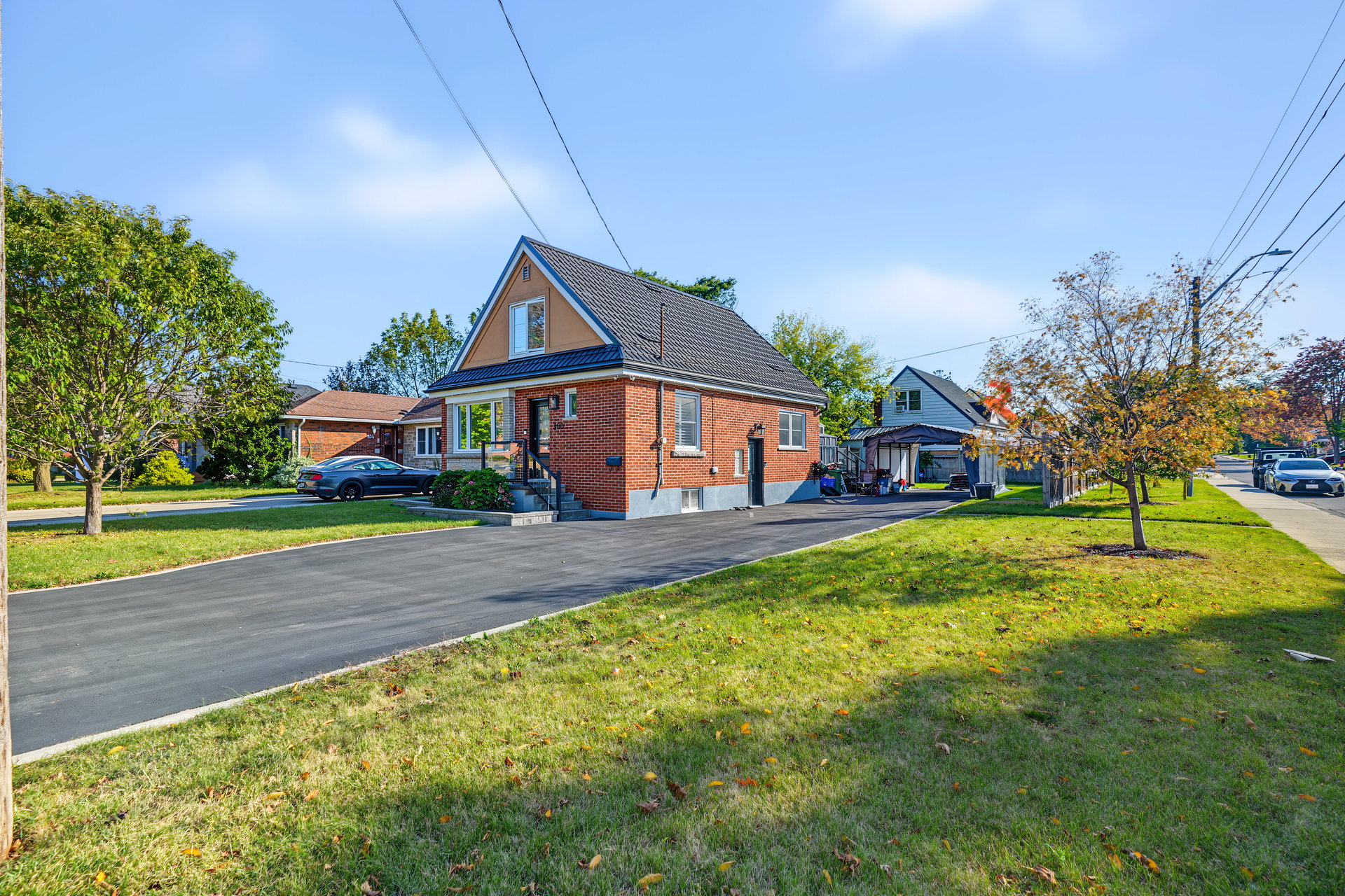 Red-brick house with a steep gabled roof, broad driveway, and front lawn.