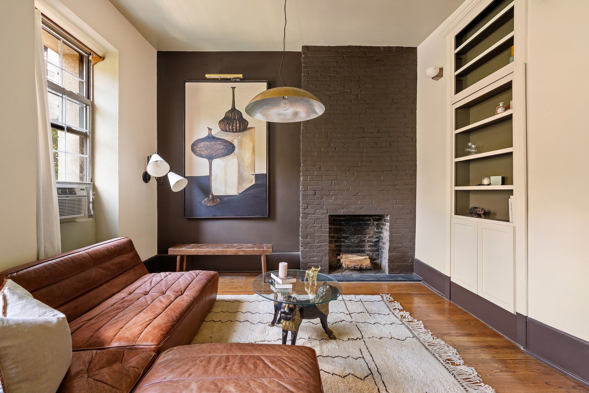 Living area with a painted brick fireplace and built-in bookcase at 207 West 21st Street, 3F.