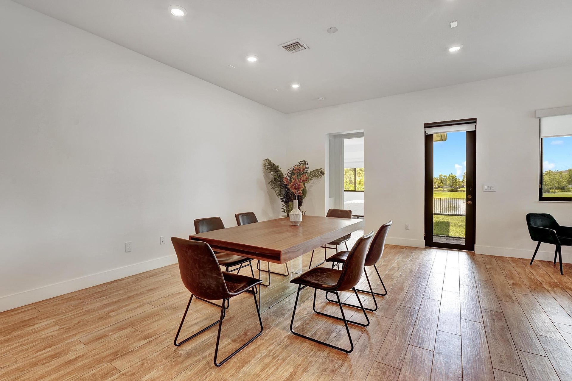 Dining room with a wood table and brown chairs beside a glass door overlooking water.