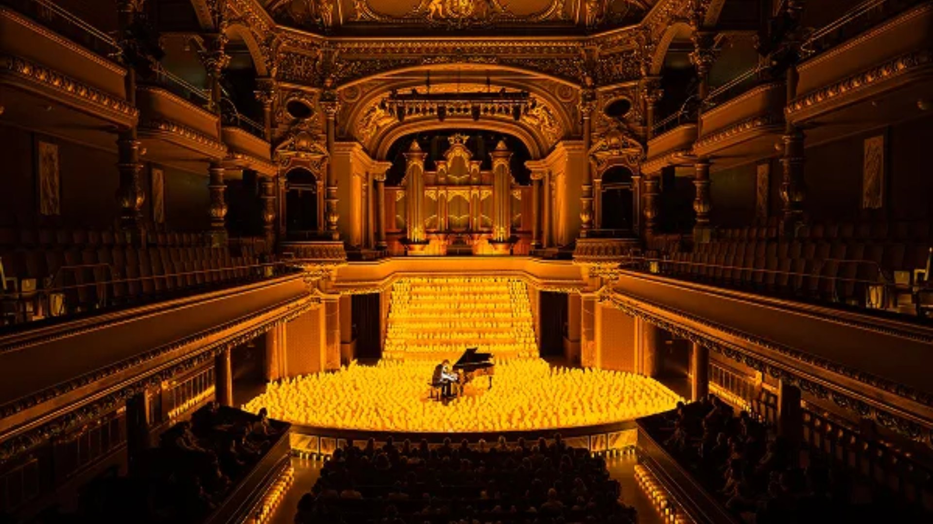 Candlelight concert with pianist performing on stage surrounded by hundreds of glowing candles in ornate golden theater, Miami cultural event by The Edit Real Estate