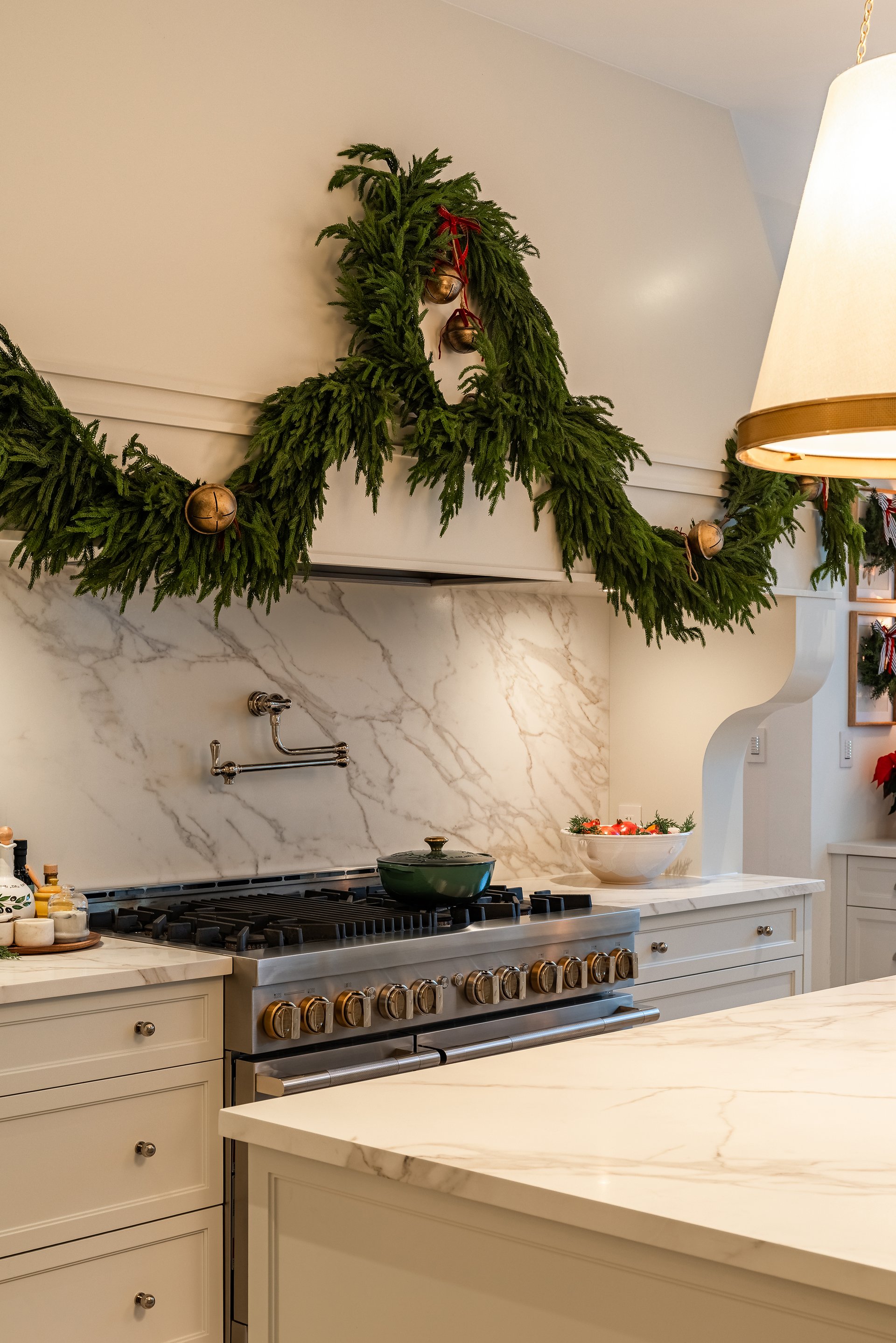 Custom kitchen hood with greenery garland and marble backsplash in an Oakville custom home decorated for the holidays.