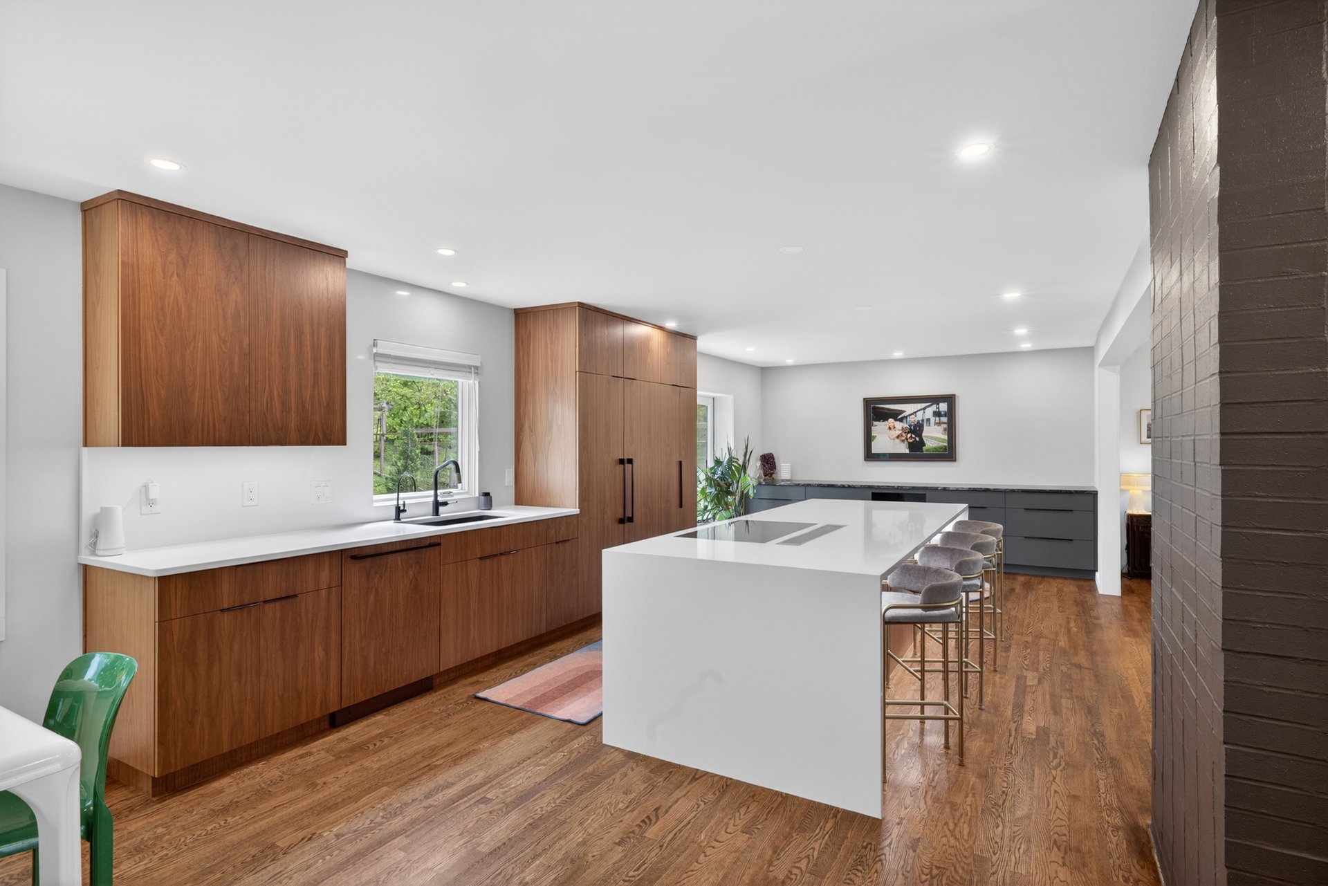 Modern kitchen with walnut cabinets, a white waterfall island, and hardwood floors.