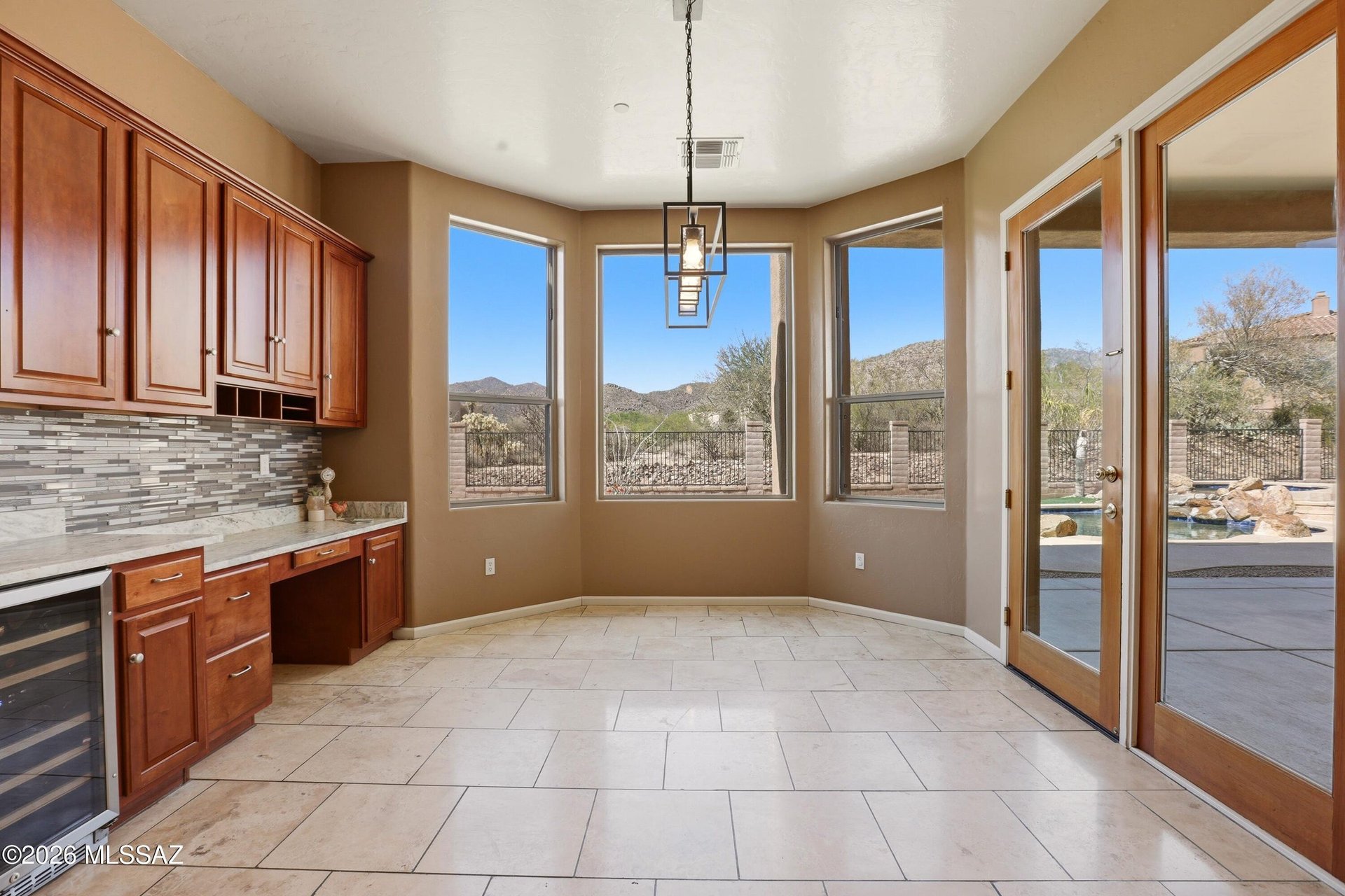 Kitchen and breakfast nook with cherry cabinets, mountain views, and glass doors opening to the pool patio.