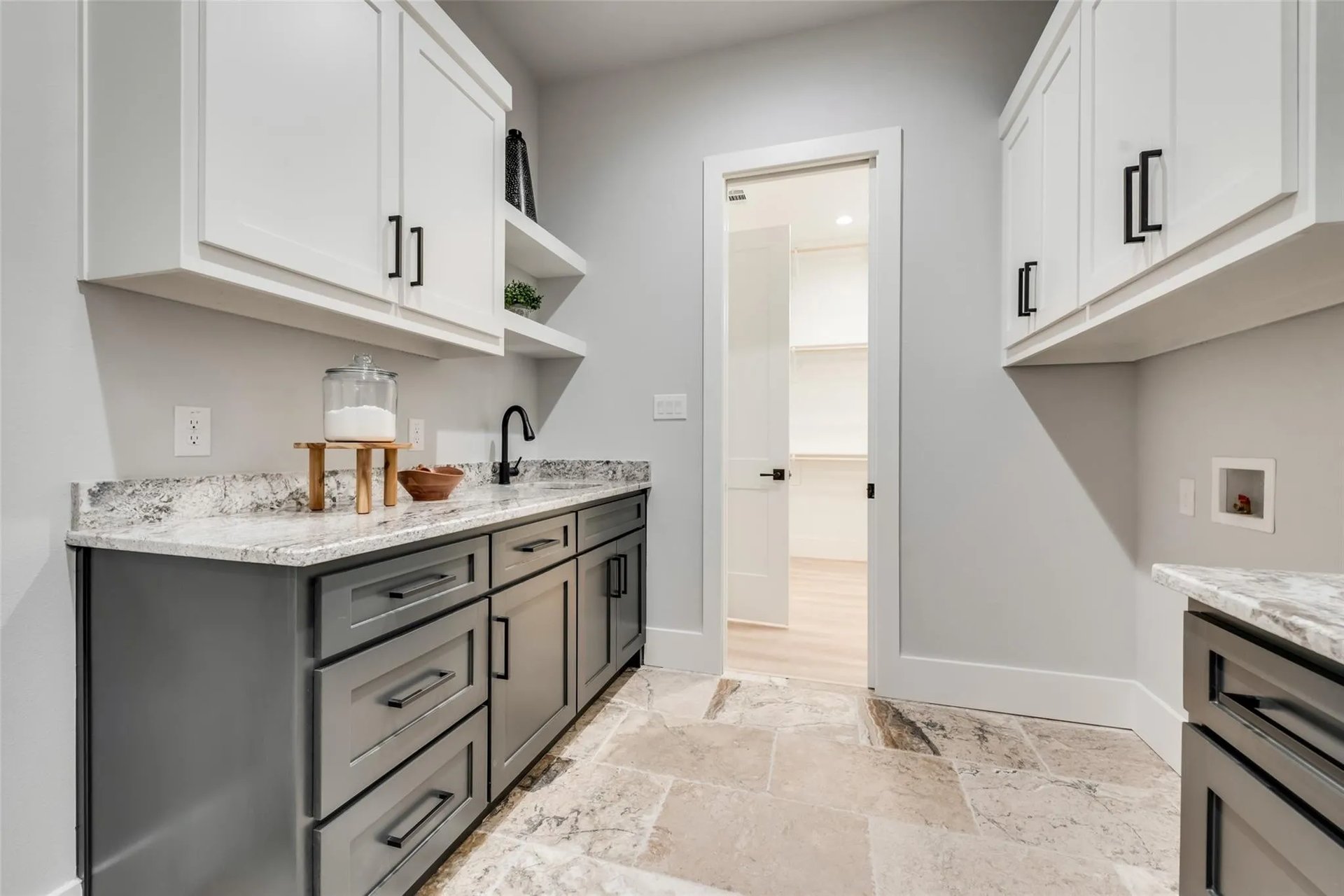 Laundry room with gray cabinetry, stone countertops, washer connections, and patterned tile flooring.