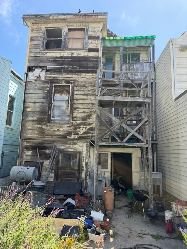 Weathered rear exterior and exposed wooden stairs at 964-966 York Street, a vacant two-unit fixer building in the Mission District, San Francisco