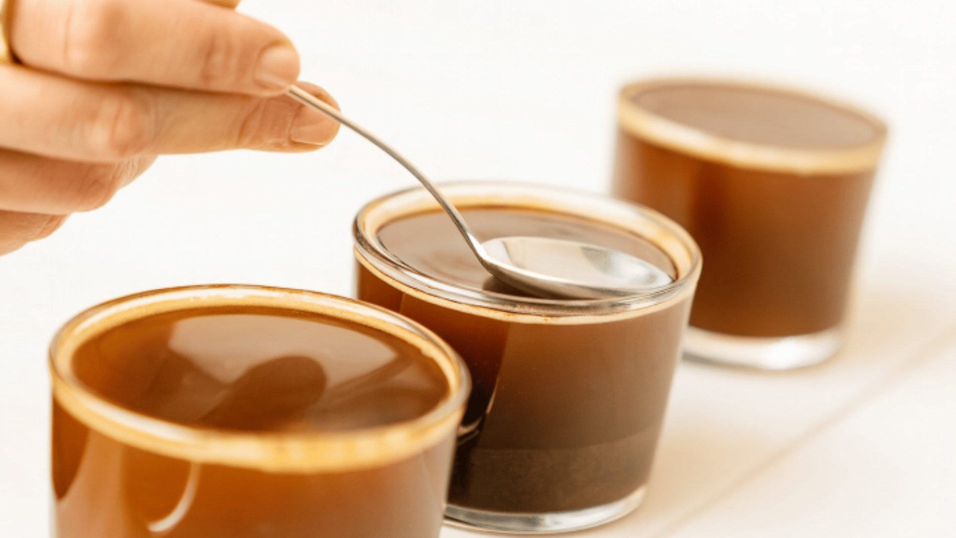 Hand stirring premium coffee in artisan cups showcasing Miami's sophisticated coffee culture - The Edit Real Estate